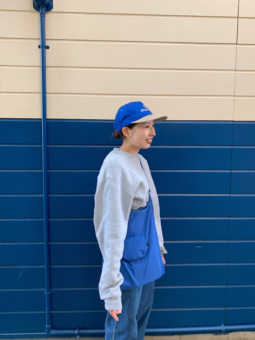 グレー系のスウェット、ブルー系のショルダーバッグ、ブルー系のデニムパンツを着用したレディースの春コーディネートの2枚目の写真