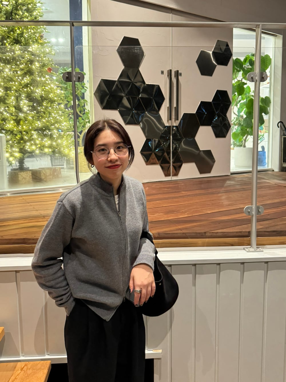 ブラック系のハンドバッグ、ブラック系のスラックス、ブラック系のスニーカーを着用したレディースの冬コーディネートの2枚目の写真