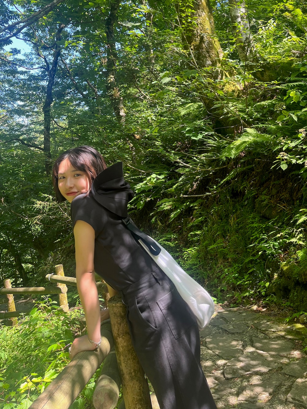 ホワイト系のショルダーバッグ、ブラック系のデニムパンツ、ブラック系のサンダルを着用したレディースの夏コーディネートの2枚目の写真