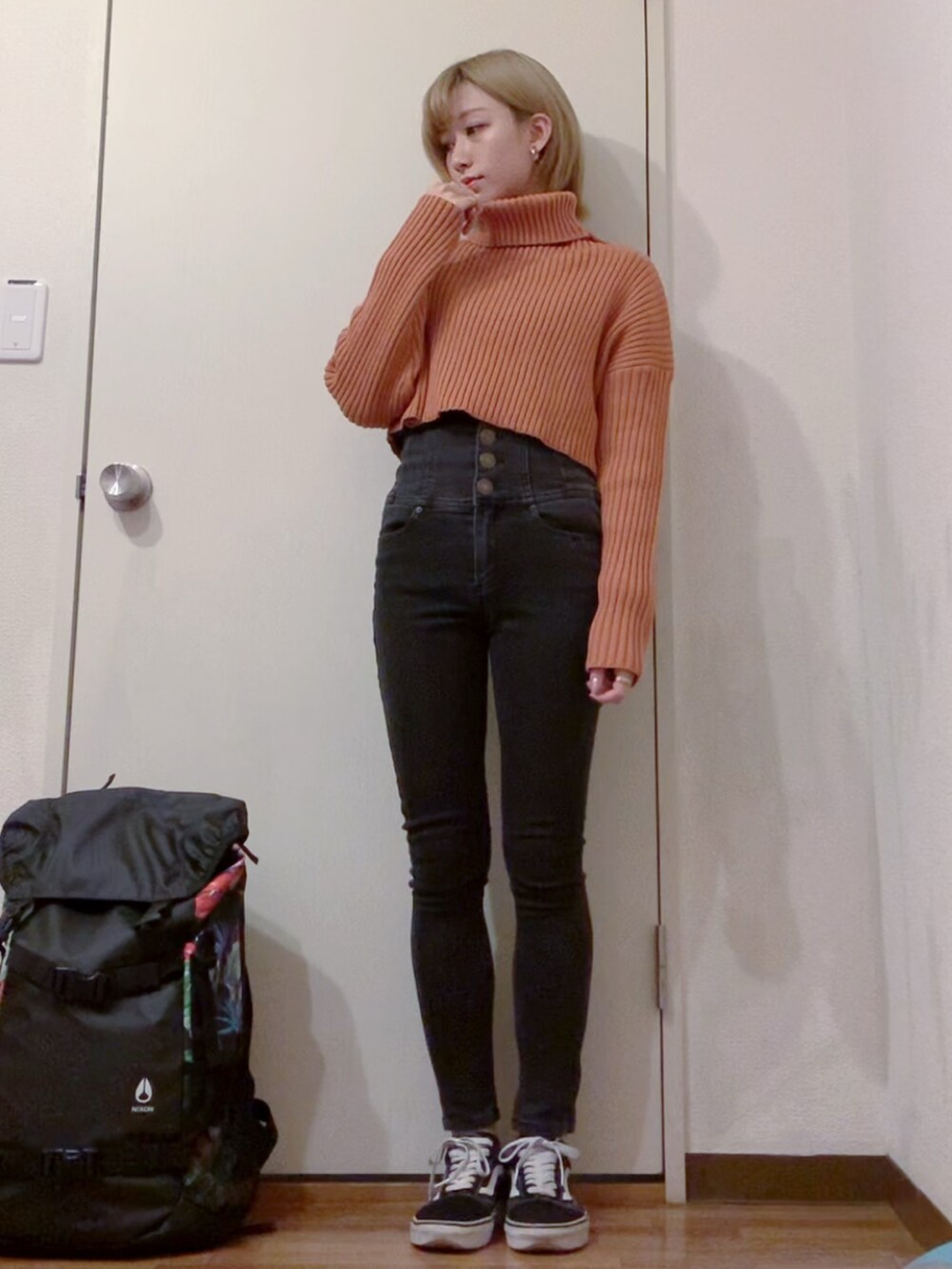 オレンジ系のニット/セーター、ブラック系のデニムパンツ、ブラック系のナイロンジャケットを着用したレディースの冬コーディネートの2枚目の写真