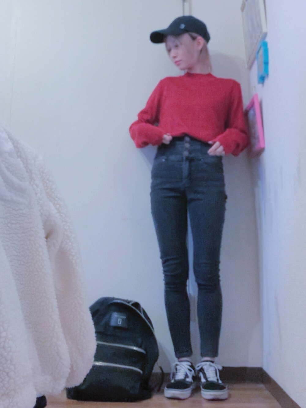 レッド系のニット/セーター、ブラック系のデニムパンツ、ブラック系のダウンジャケット/コートを着用したレディースの冬コーディネートの2枚目の写真