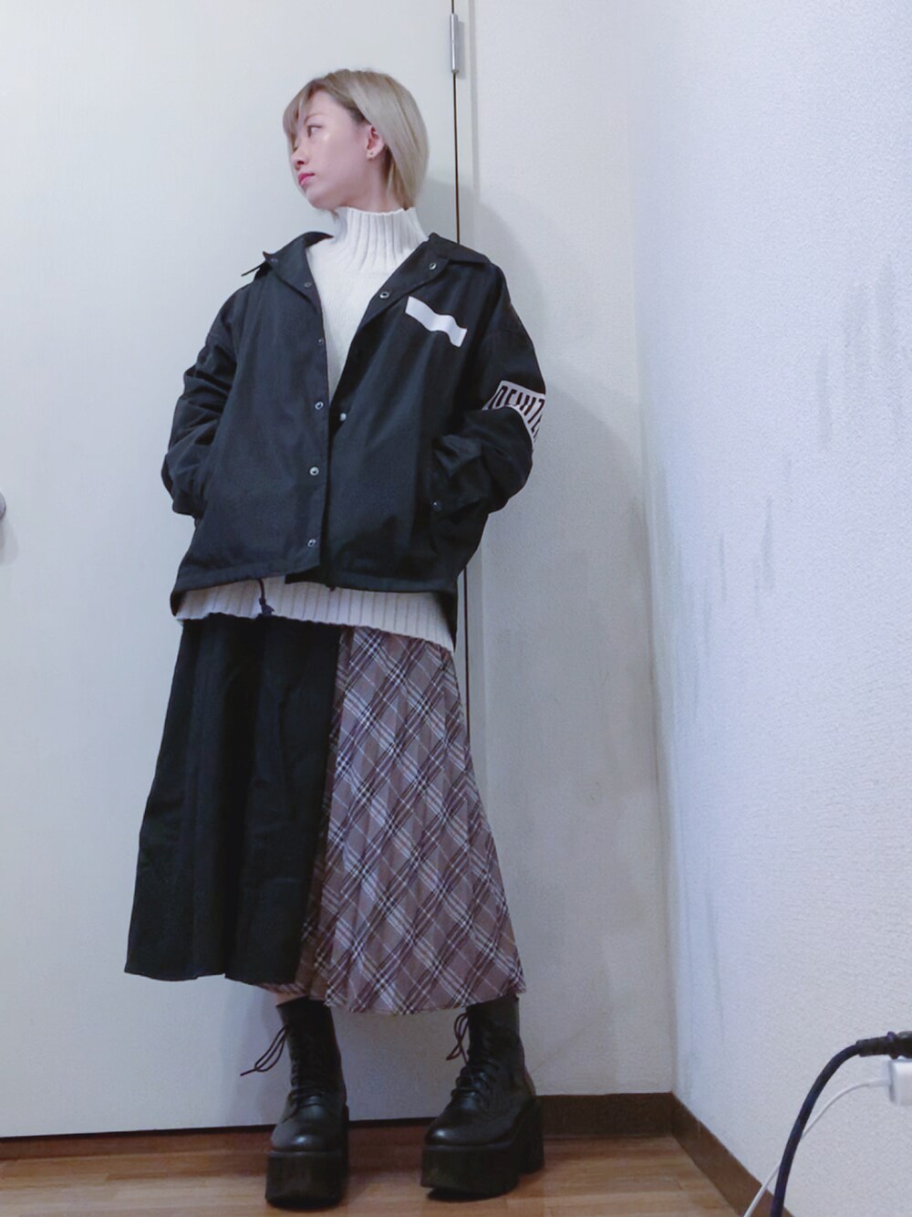 ホワイト系のニット/セーター、ブラック系のナイロンジャケット、ブラック系のスカートを着用したレディースの春コーディネートの3枚目の写真