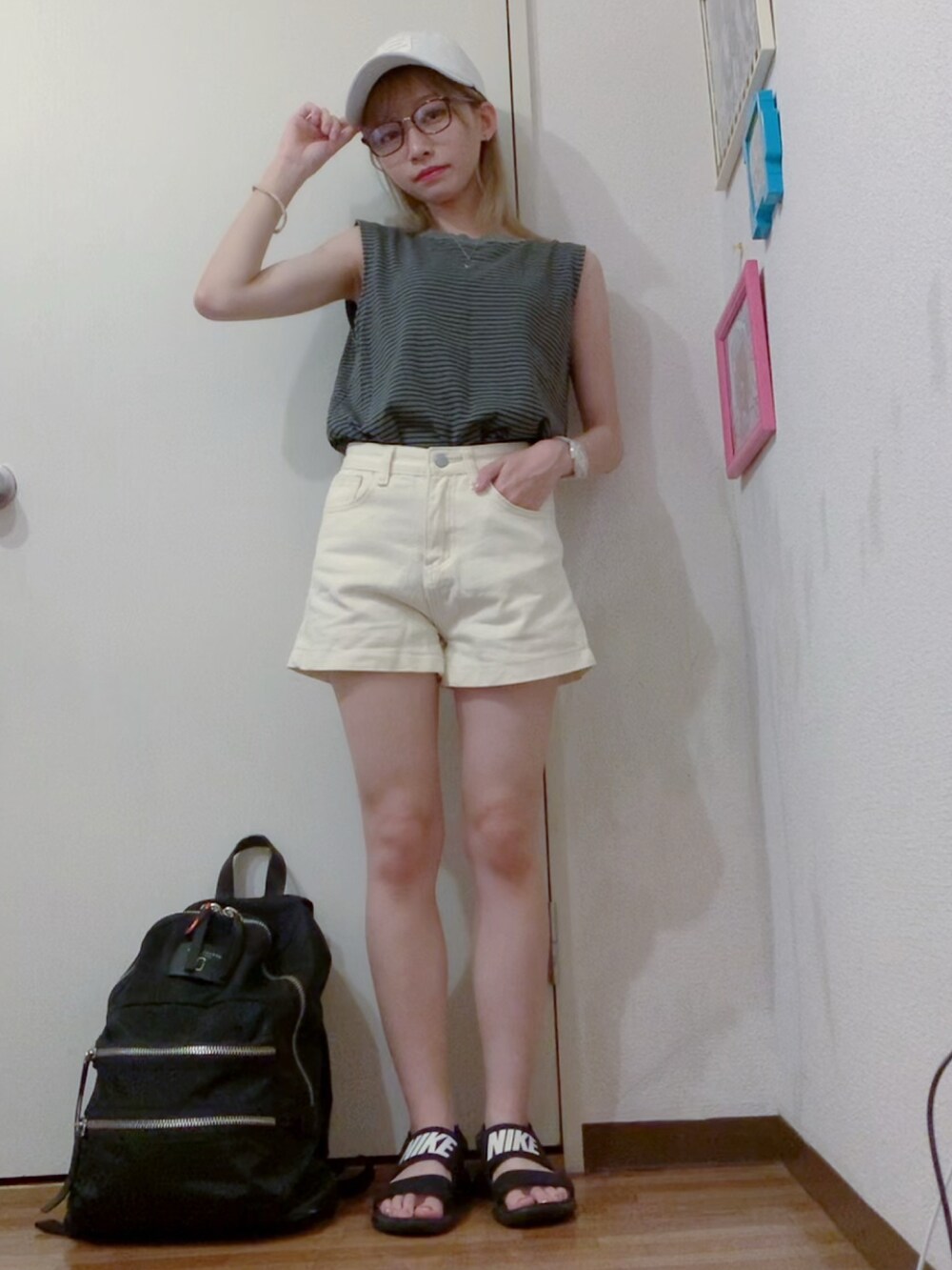 グレー系のタンクトップ、ホワイト系のデニムパンツ、ブラック系のサンダルを着用したレディースの夏コーディネートの3枚目の写真