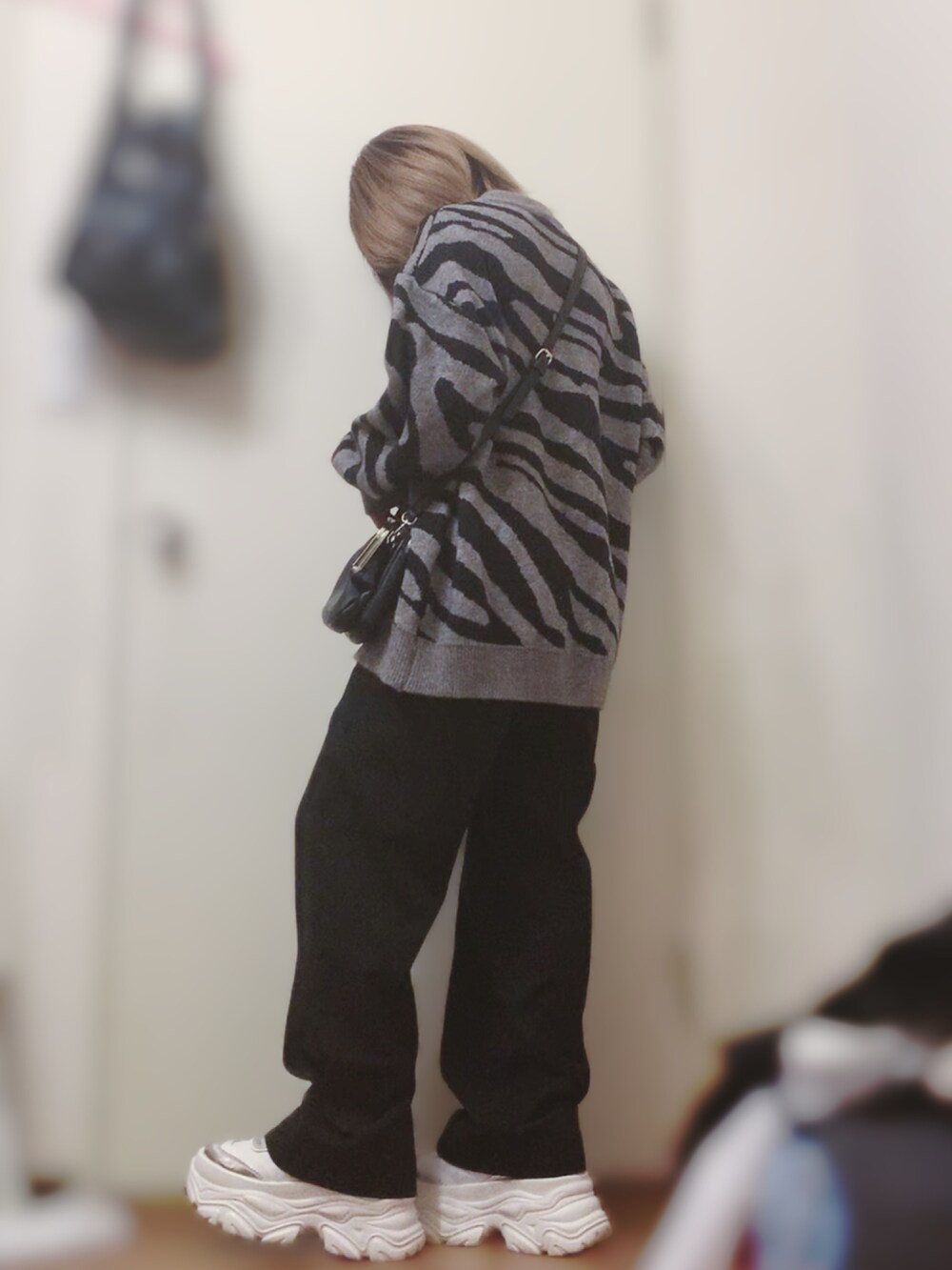 グレー系のニット/セーター、ブラック系のその他パンツ、ホワイト系のスニーカーを着用したレディースの春コーディネートの3枚目の写真