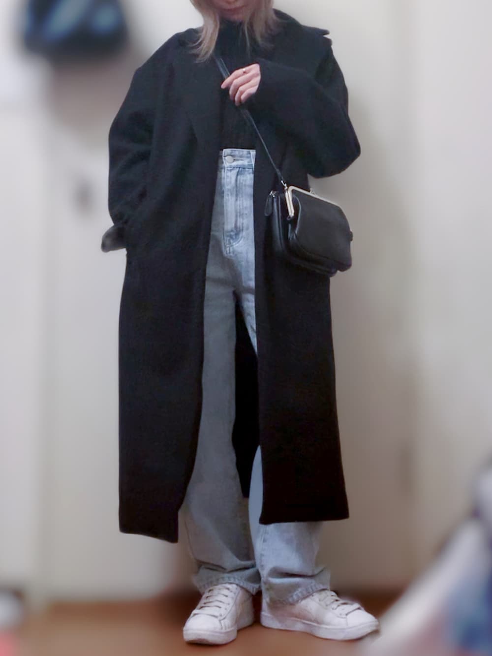 ブラック系のニット/セーター、ブルー系のデニムパンツ、ホワイト系のスニーカーを着用したレディースの春コーディネートの3枚目の写真