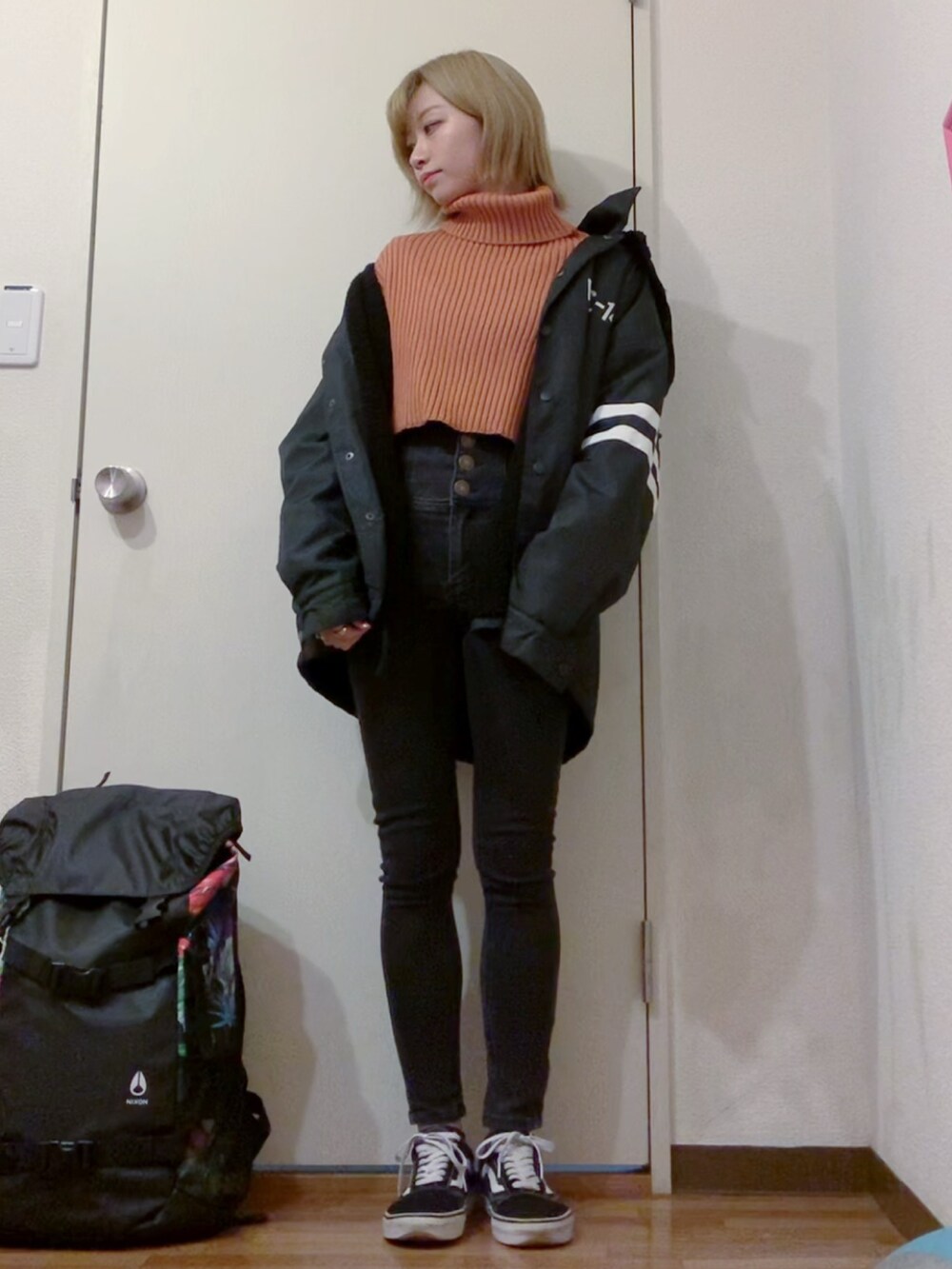 オレンジ系のニット/セーター、ブラック系のデニムパンツ、ブラック系のナイロンジャケットを着用したレディースの冬コーディネートの4枚目の写真