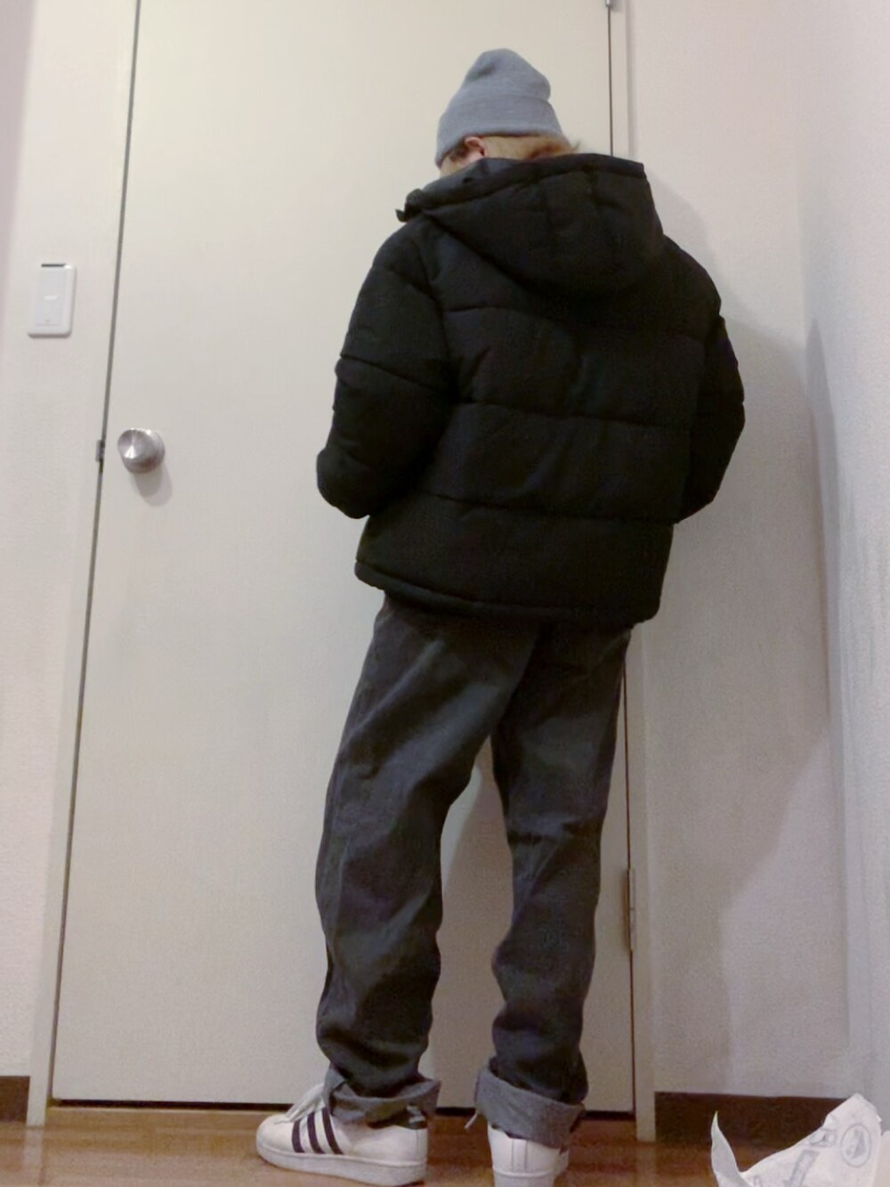 ブラック系のスウェット、ブラック系のデニムパンツ、ホワイト系のスニーカーを着用したレディースの冬コーディネートの3枚目の写真