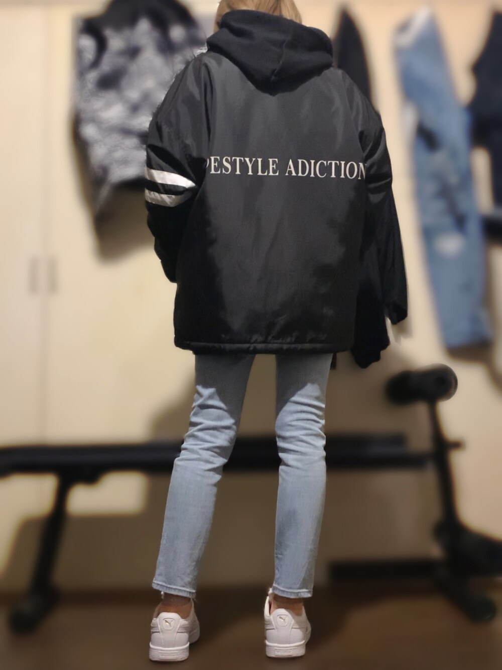 ブラック系のパーカー、ブルー系のデニムパンツ、ホワイト系のスニーカーを着用したレディースの冬コーディネートの2枚目の写真