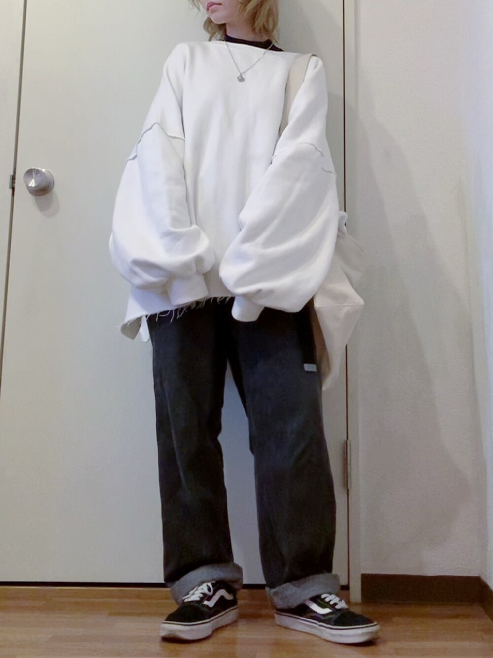 ホワイト系のスウェット、ブラック系のデニムパンツ、ブラック系のスニーカーを着用したレディースの冬コーディネートの2枚目の写真