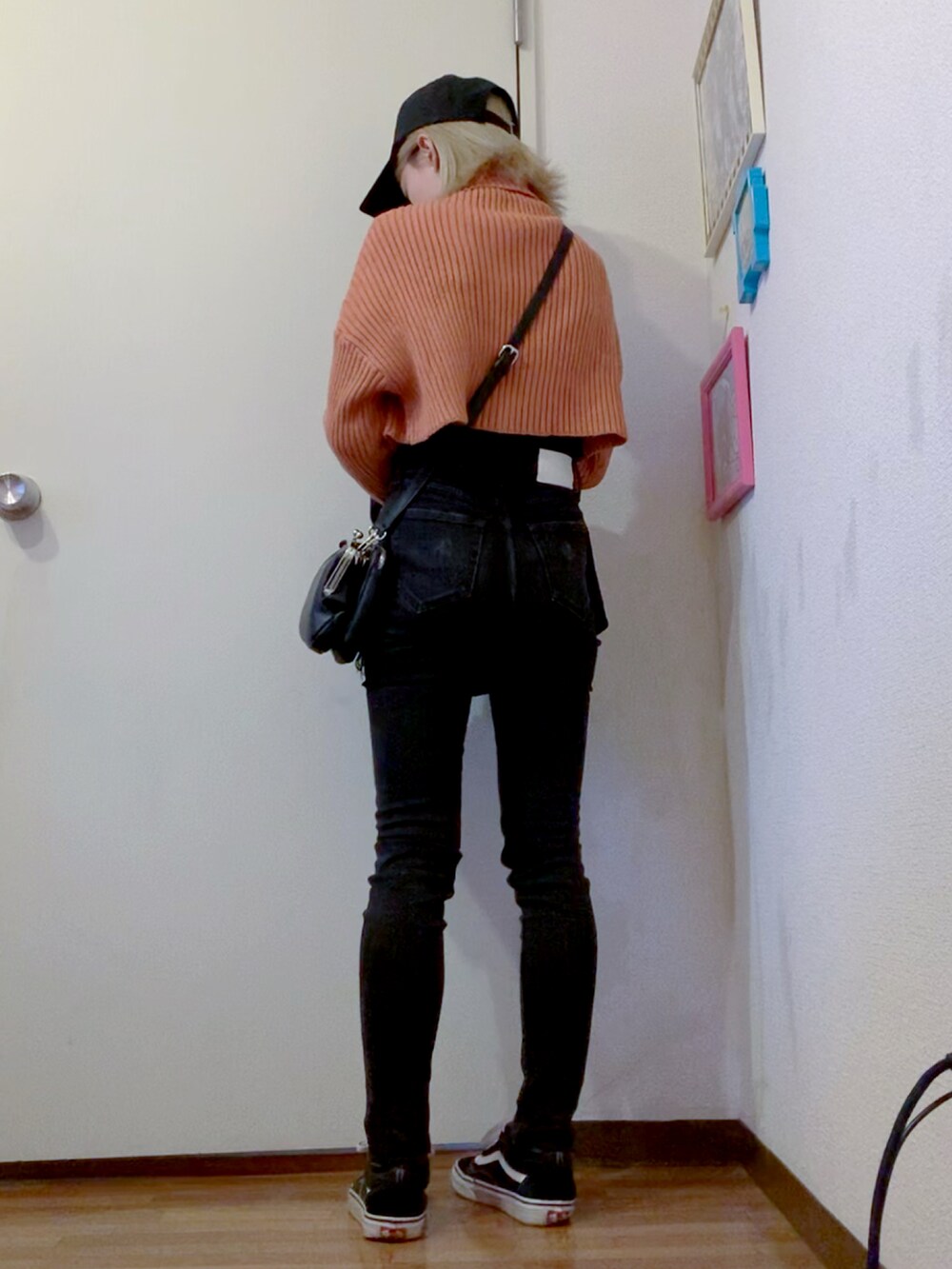 オレンジ系のニット/セーター、ブラック系のデニムパンツ、ブラック系のナイロンジャケットを着用したレディースの秋コーディネートの3枚目の写真