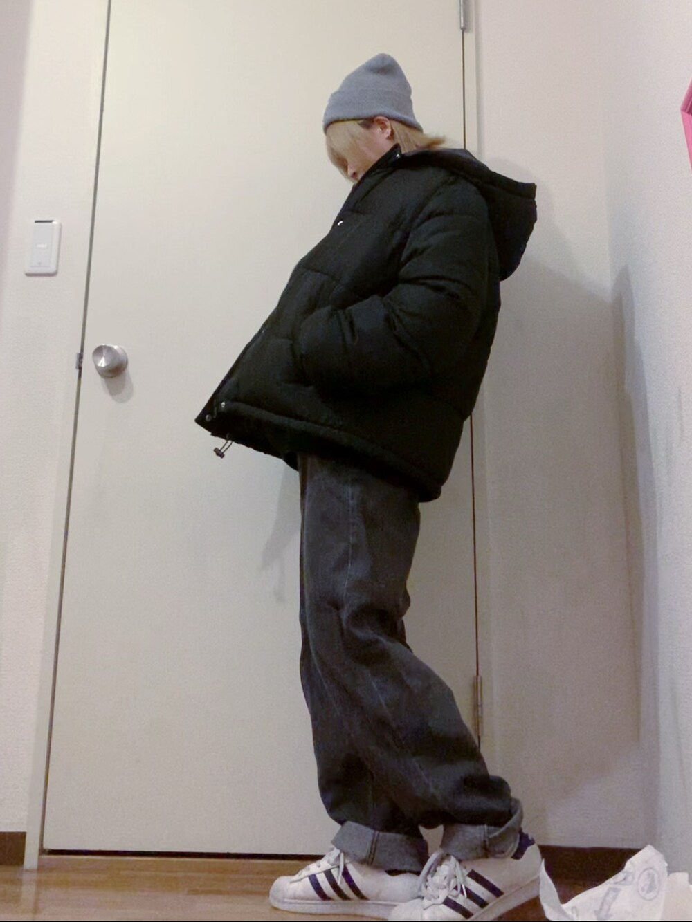 ブラック系のスウェット、ブラック系のデニムパンツ、ホワイト系のスニーカーを着用したレディースの冬コーディネートの2枚目の写真