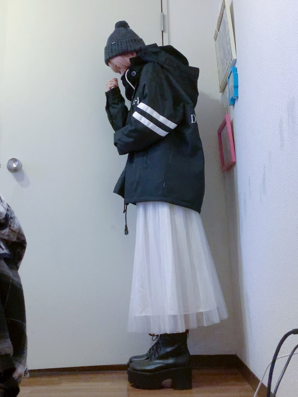 ブラック系のナイロンジャケット、ホワイト系のスカート、ブラック系のブーツを着用したレディースの秋コーディネートの2枚目の写真