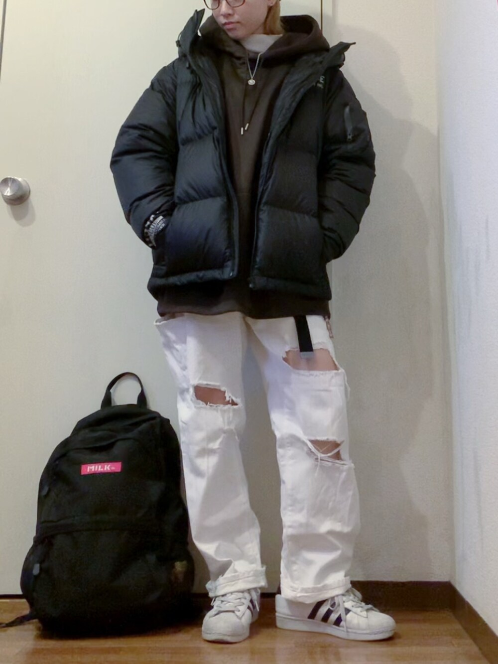 ブラック系のパーカー、ホワイト系のデニムパンツ、ホワイト系のニット/セーターを着用したレディースの冬コーディネートの4枚目の写真