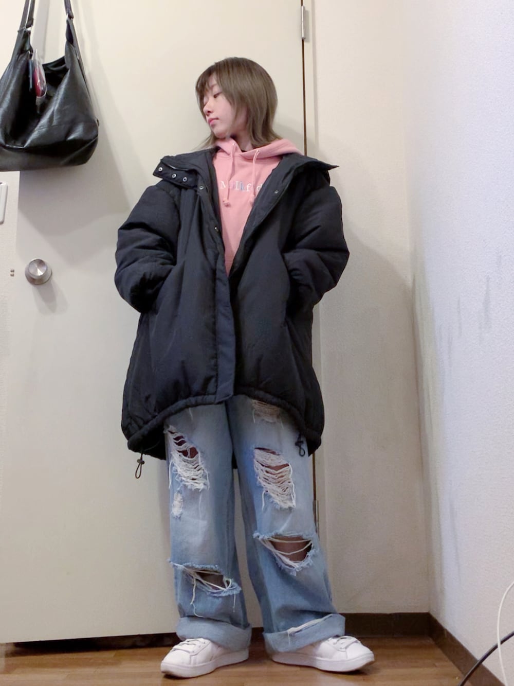 ピンク系のパーカー、ブルー系のデニムパンツ、ホワイト系のスニーカーを着用したレディースの冬コーディネートの2枚目の写真