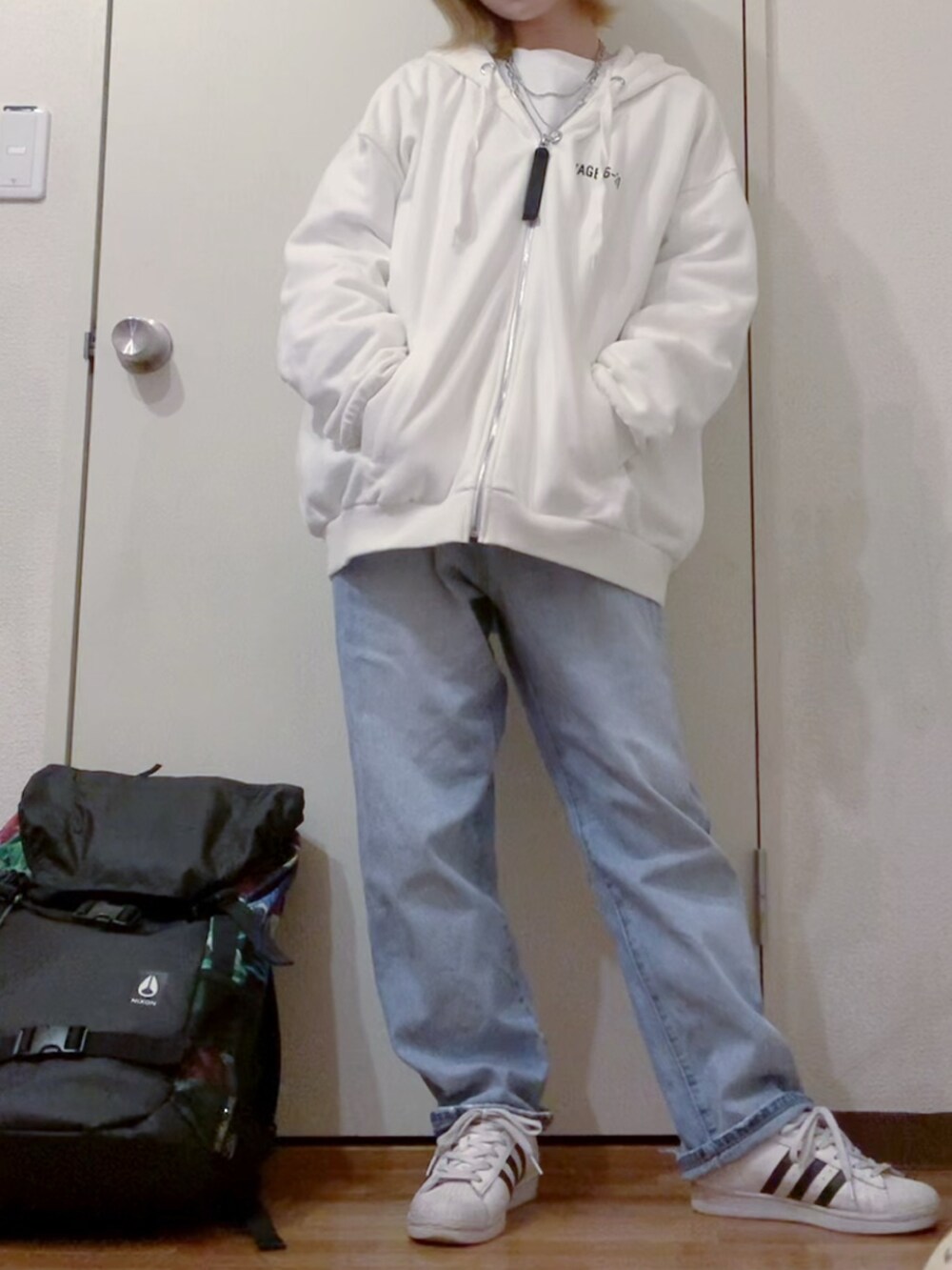 ホワイト系のパーカー、ホワイト系のスウェット、ブルー系のデニムパンツを着用したレディースの冬コーディネートの4枚目の写真