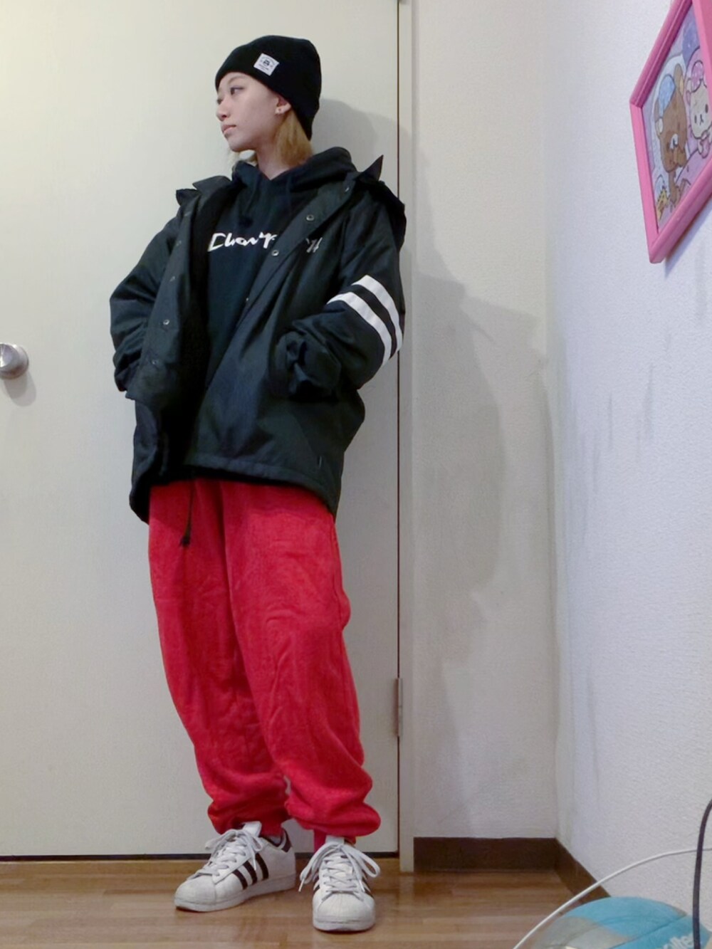 ブラック系のパーカー、ブラック系のナイロンジャケット、レッド系のスウェットパンツを着用したレディースの冬コーディネートの2枚目の写真