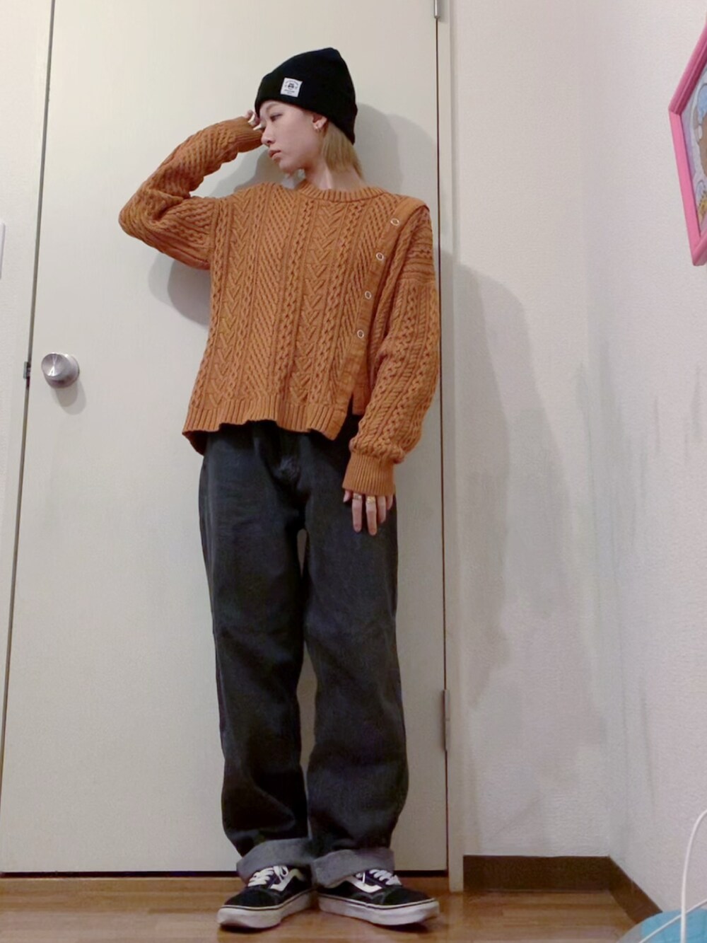 オレンジ系のニット/セーター、ブラック系のデニムパンツ、ブラック系のダウンジャケット/コートを着用したレディースの冬コーディネートの2枚目の写真