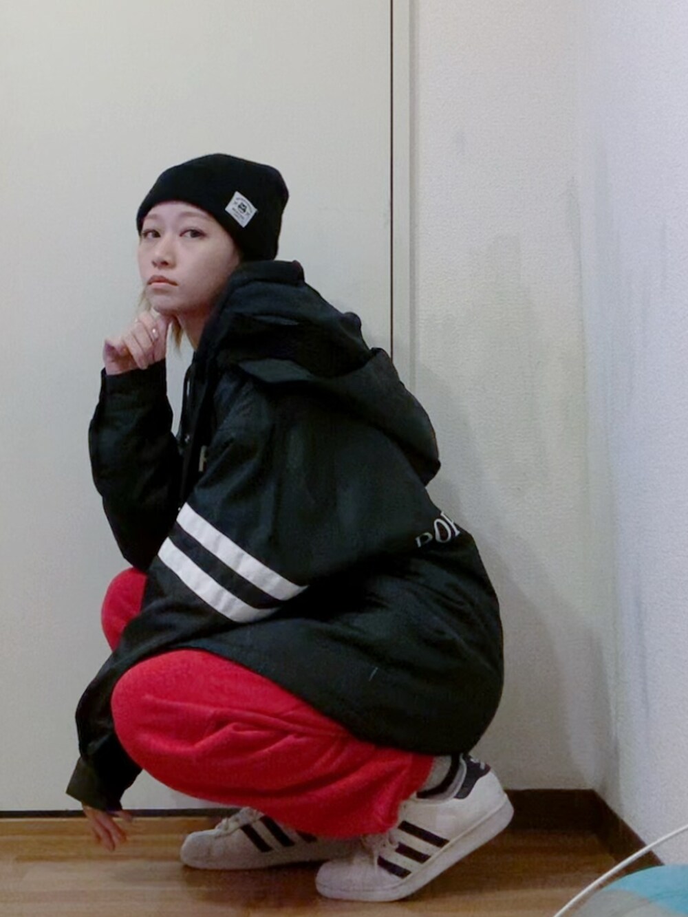 ブラック系のパーカー、ブラック系のナイロンジャケット、レッド系のスウェットパンツを着用したレディースの冬コーディネートの3枚目の写真