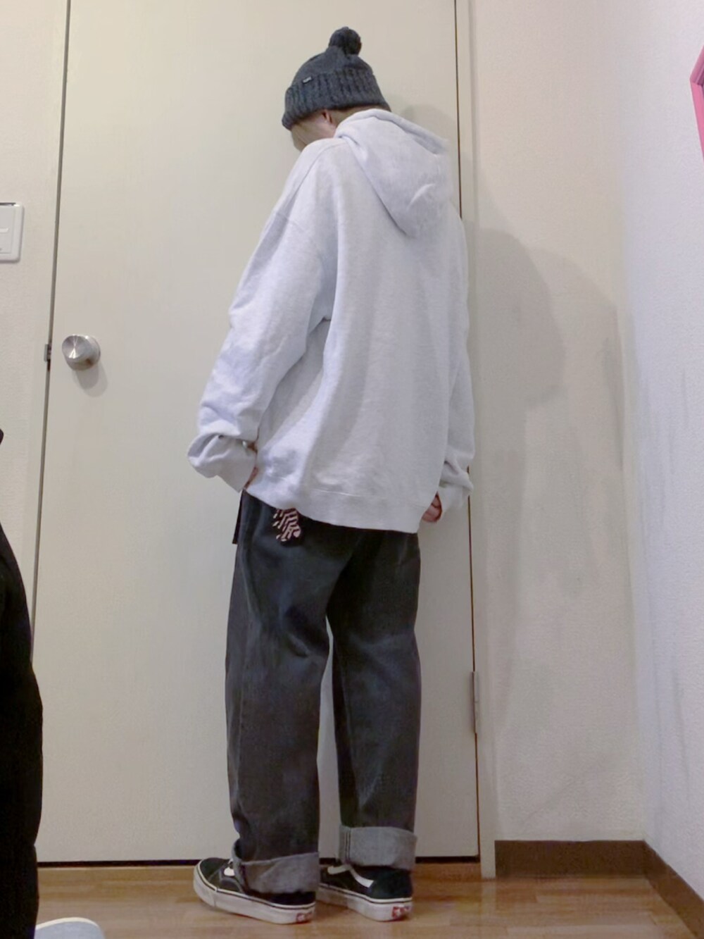 グレー系のパーカー、ブラック系のデニムパンツ、ブラック系のチェスターコートを着用したレディースの冬コーディネートの3枚目の写真