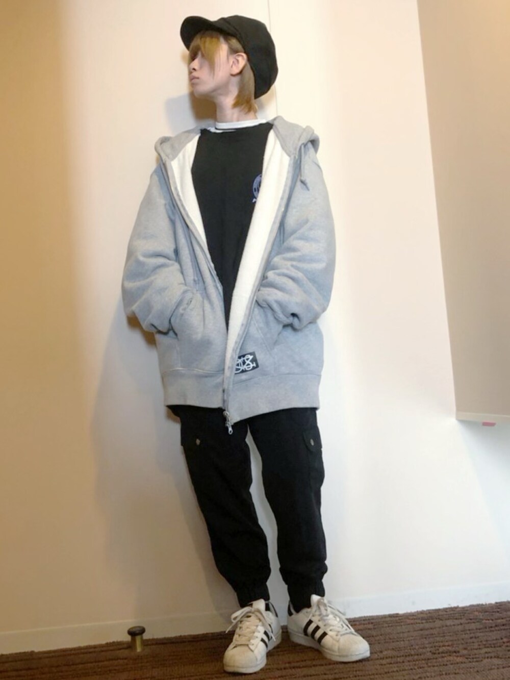 グレー系のパーカー、ブラック系のカーゴパンツ、ホワイト系のスニーカーを着用したレディースの秋コーディネートの2枚目の写真