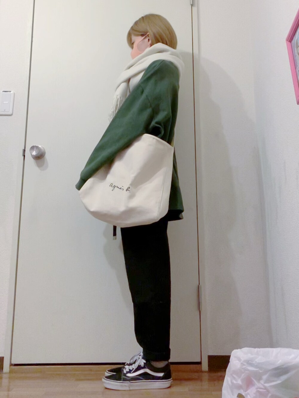 グリーン系のスウェット、ブラック系のデニムパンツ、ブラック系のスニーカーを着用したレディースの冬コーディネートの2枚目の写真