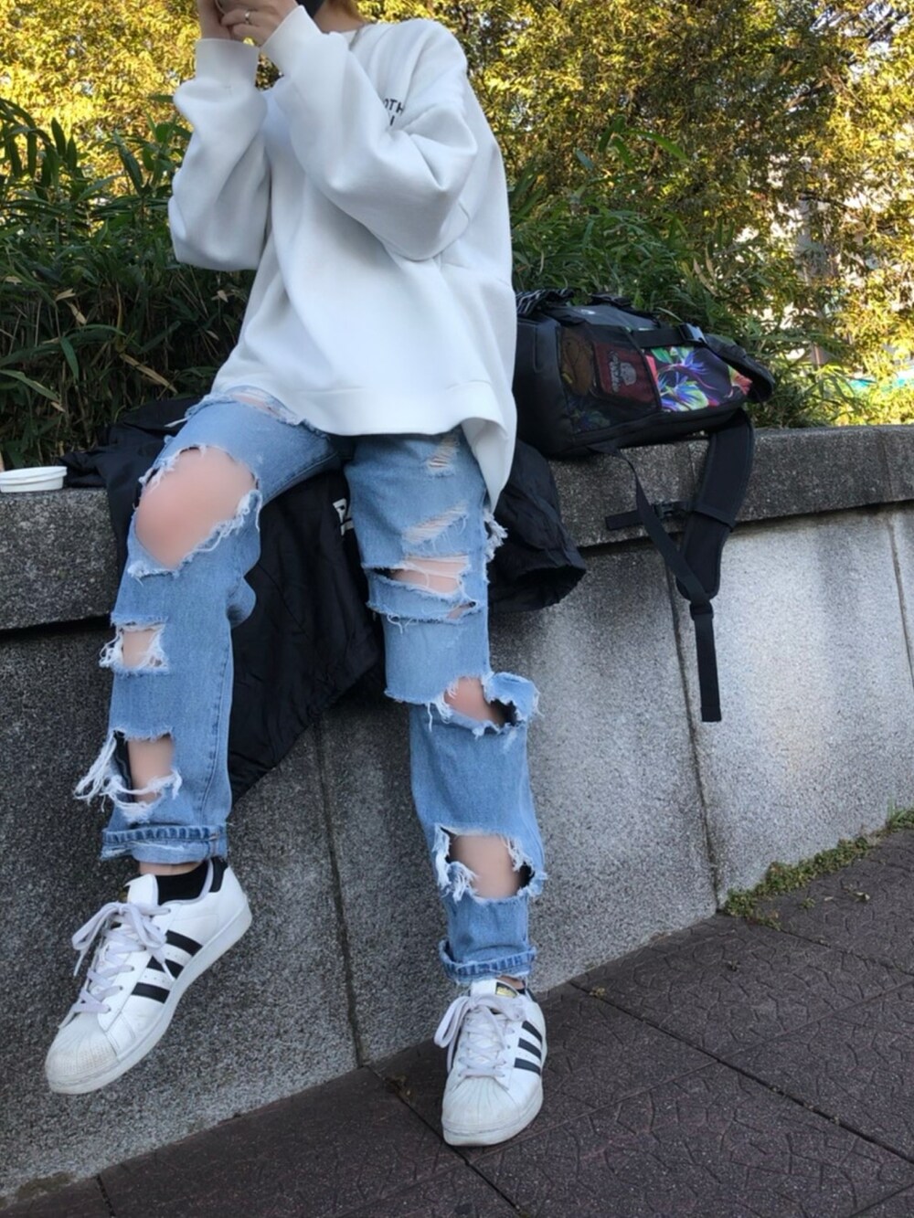 ホワイト系のスウェット、ホワイト系のブルゾン、ブルー系のデニムパンツを着用したレディースの秋コーディネートの4枚目の写真