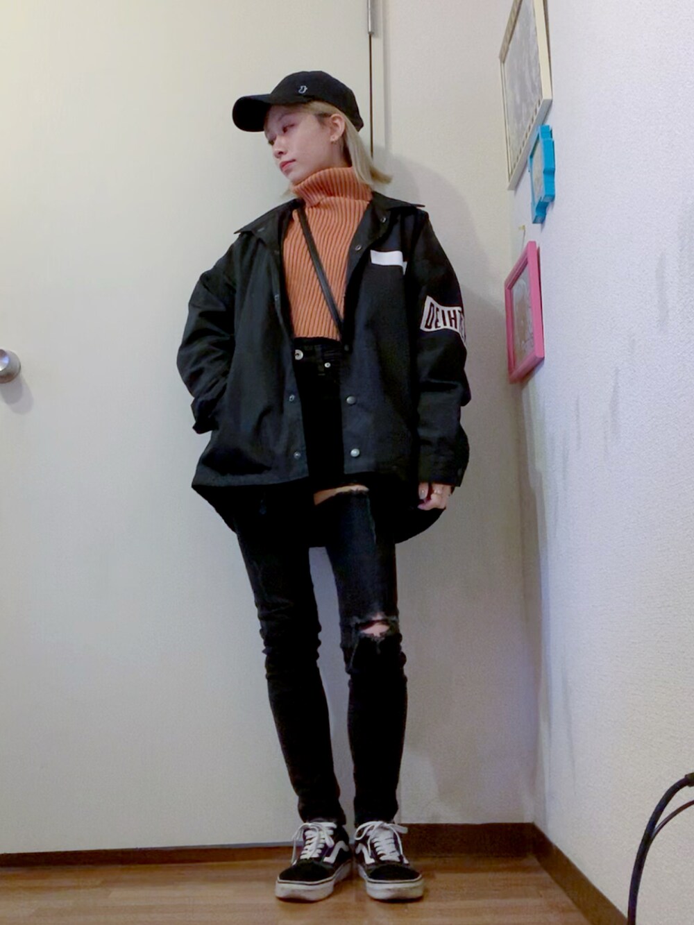 オレンジ系のニット/セーター、ブラック系のデニムパンツ、ブラック系のナイロンジャケットを着用したレディースの秋コーディネートの2枚目の写真