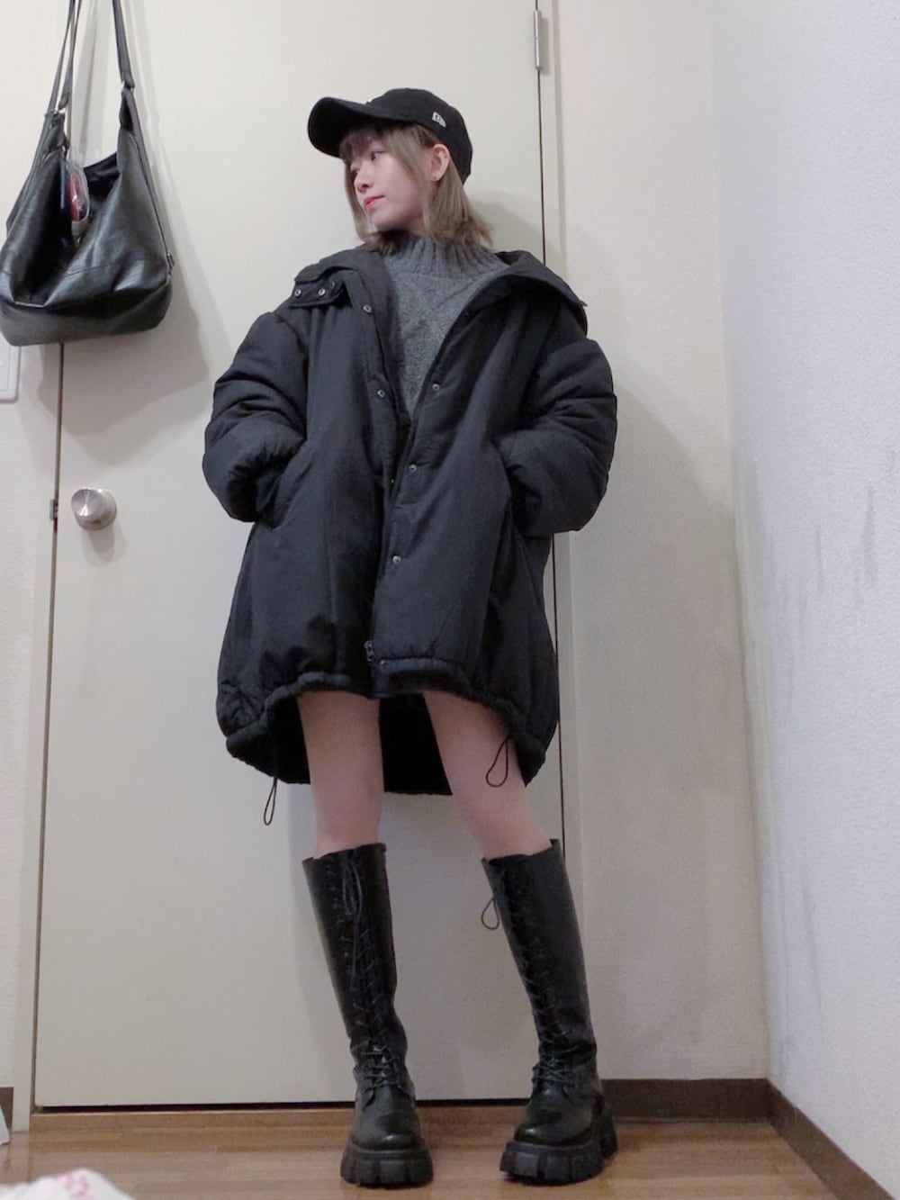 グレー系のニット/セーター、ブラック系のブーツ、ブラック系のダウンジャケット/コートを着用したレディースの冬コーディネートの3枚目の写真