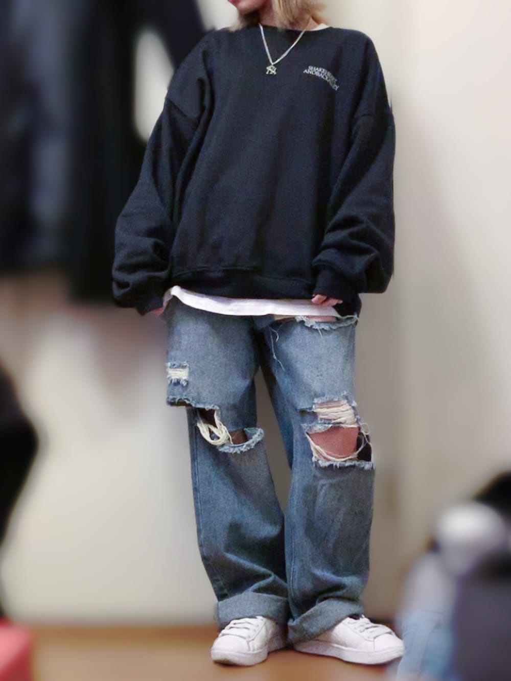 ブラック系のスウェット、ホワイト系のスニーカー、ブラック系のチェスターコートを着用したレディースの春コーディネートの2枚目の写真