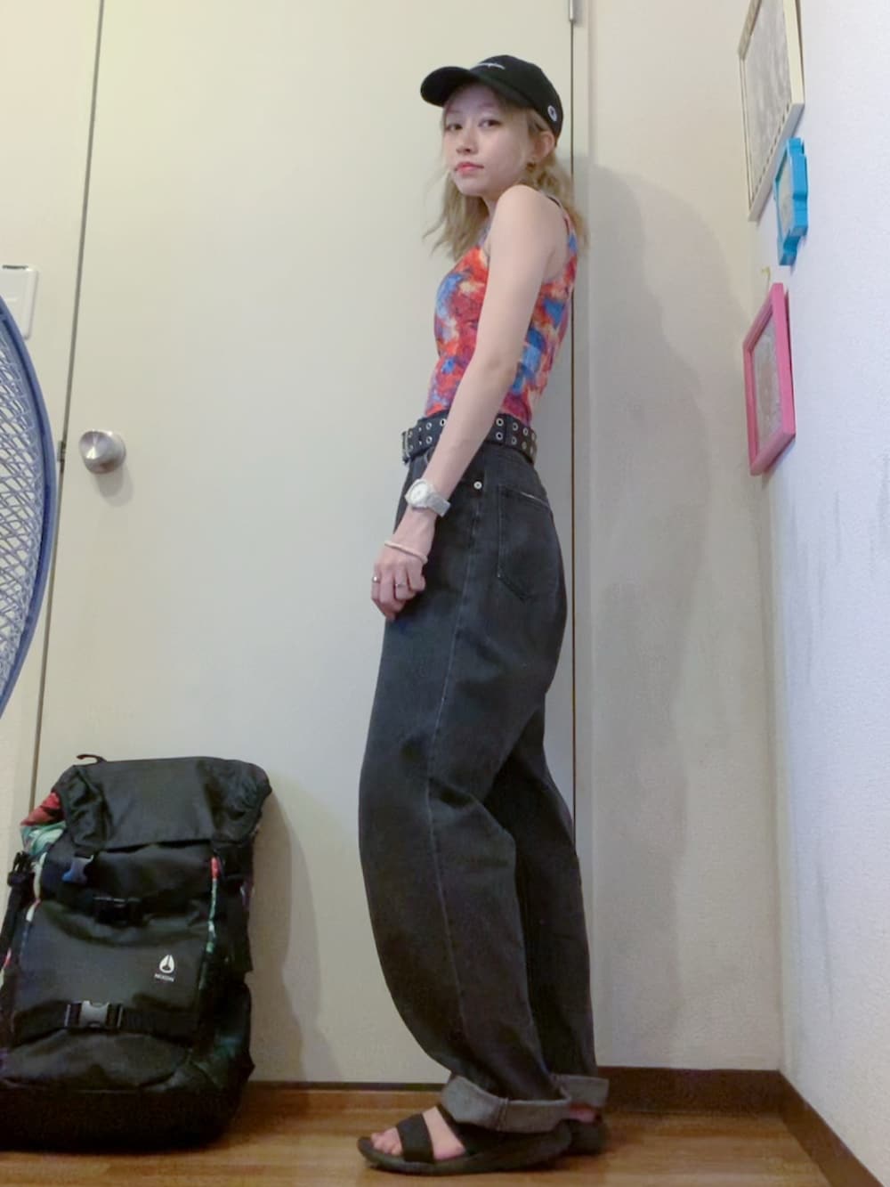 レッド系のタンクトップ、ブラック系のデニムパンツ、ブラック系のサンダルを着用したレディースの夏コーディネートの2枚目の写真