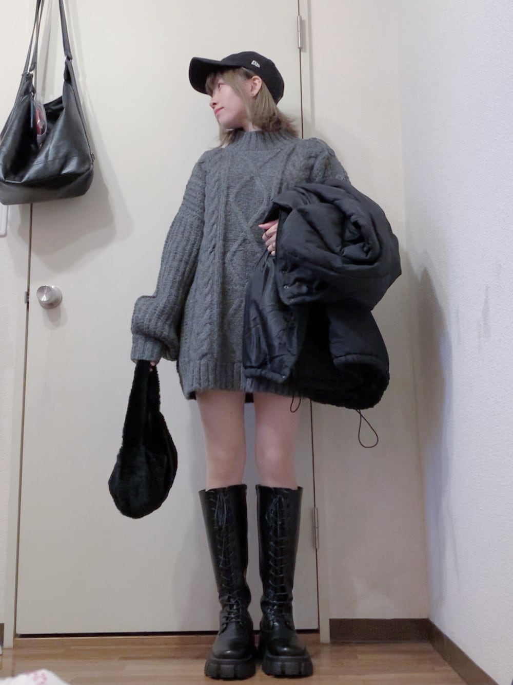 グレー系のニット/セーター、ブラック系のブーツ、ブラック系のダウンジャケット/コートを着用したレディースの冬コーディネートの4枚目の写真