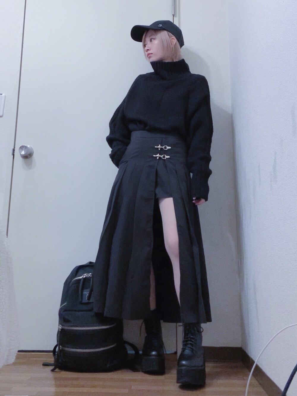 ブラック系のニット/セーター、ブラック系のスカート、ブラック系のチェスターコートを着用したレディースの冬コーディネートの2枚目の写真