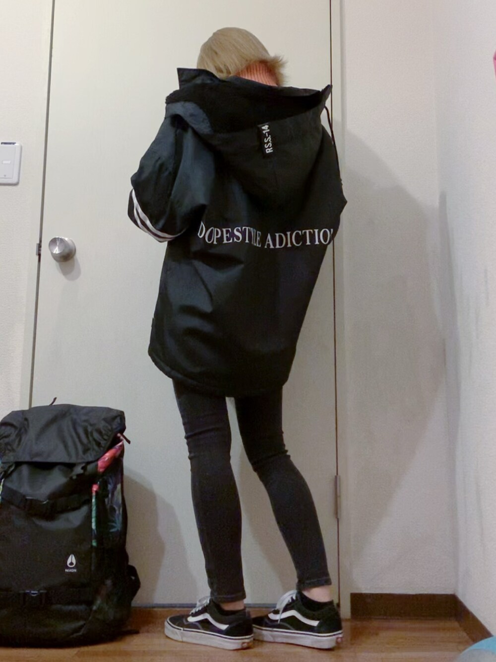 オレンジ系のニット/セーター、ブラック系のデニムパンツ、ブラック系のナイロンジャケットを着用したレディースの冬コーディネートの3枚目の写真