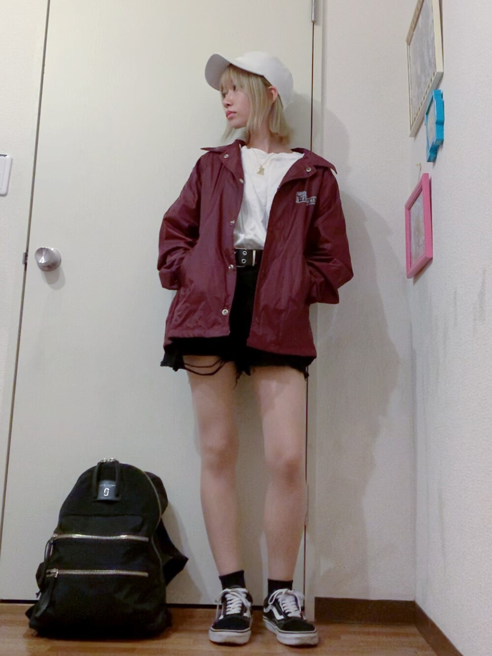 レッド系のナイロンジャケット、ブラック系のデニムパンツ、ブラック系のスニーカーを着用したレディースの秋コーディネートの3枚目の写真