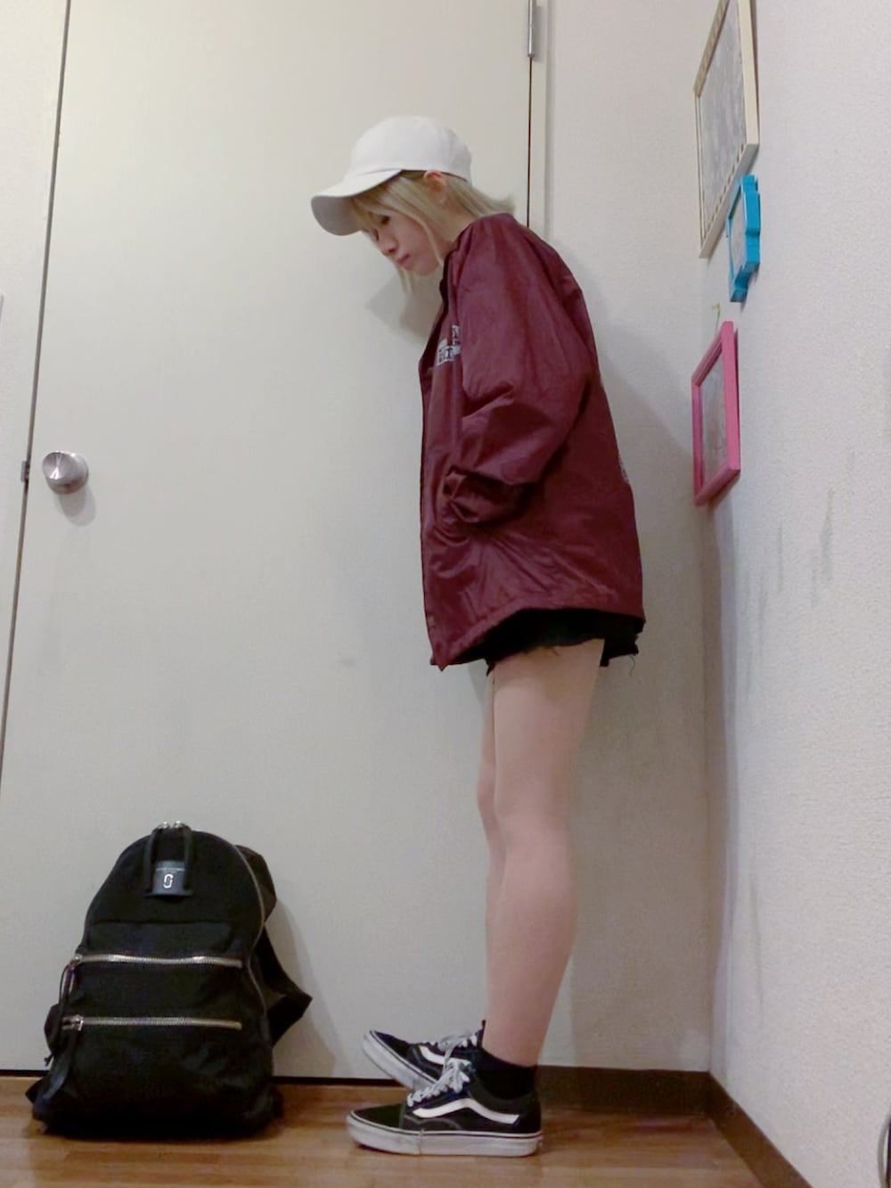 レッド系のナイロンジャケット、ブラック系のデニムパンツ、ブラック系のスニーカーを着用したレディースの秋コーディネートの2枚目の写真