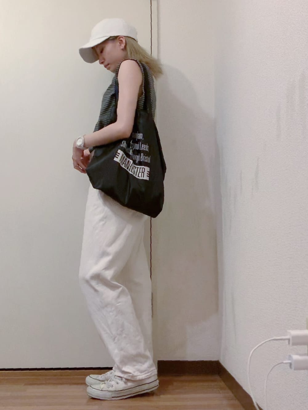 グレー系のタンクトップ、ホワイト系のデニムパンツ、ホワイト系のスニーカーを着用したレディースの夏コーディネートの3枚目の写真