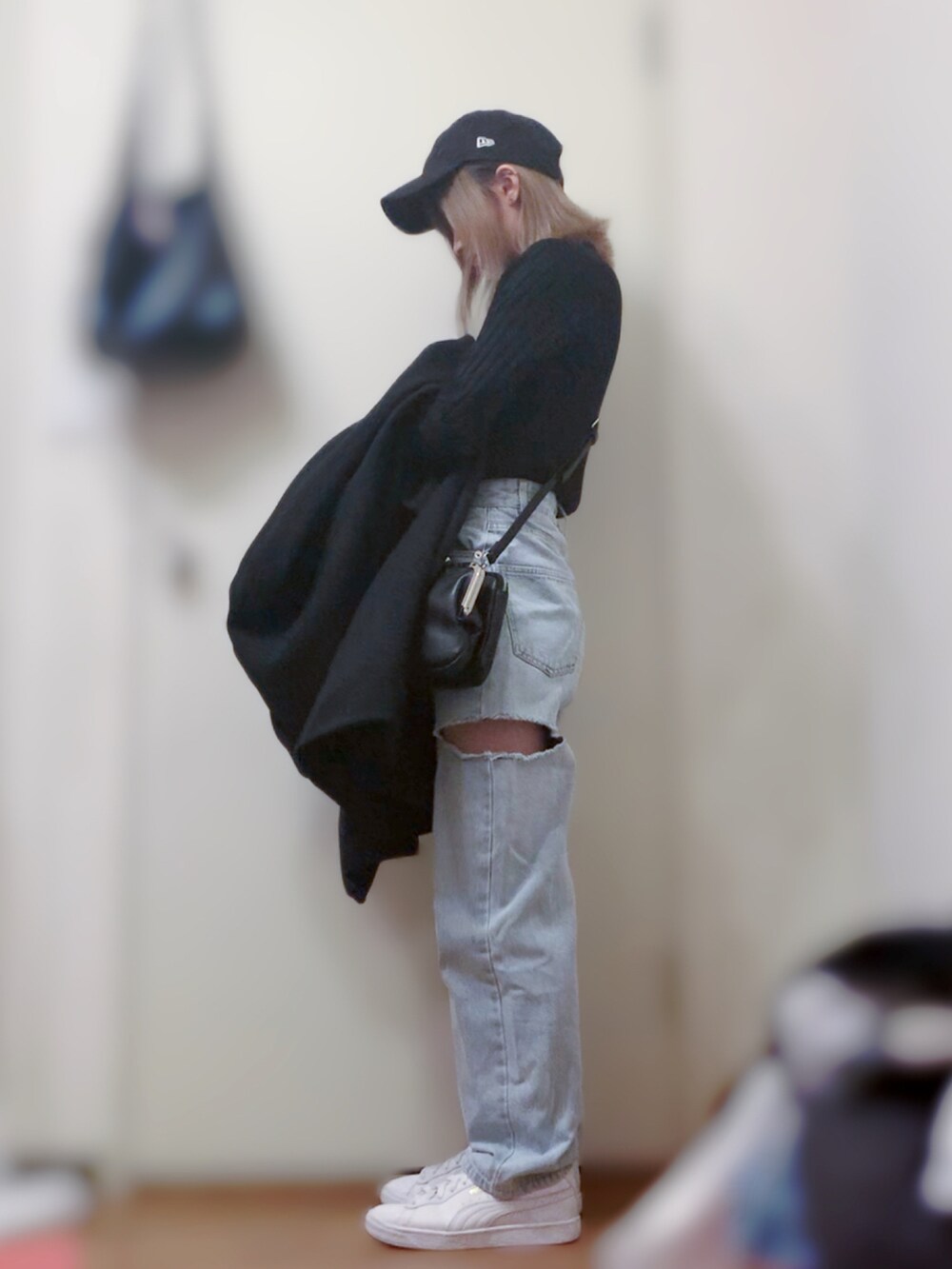 ブラック系のニット/セーター、ブルー系のデニムパンツ、ホワイト系のスニーカーを着用したレディースの春コーディネートの2枚目の写真