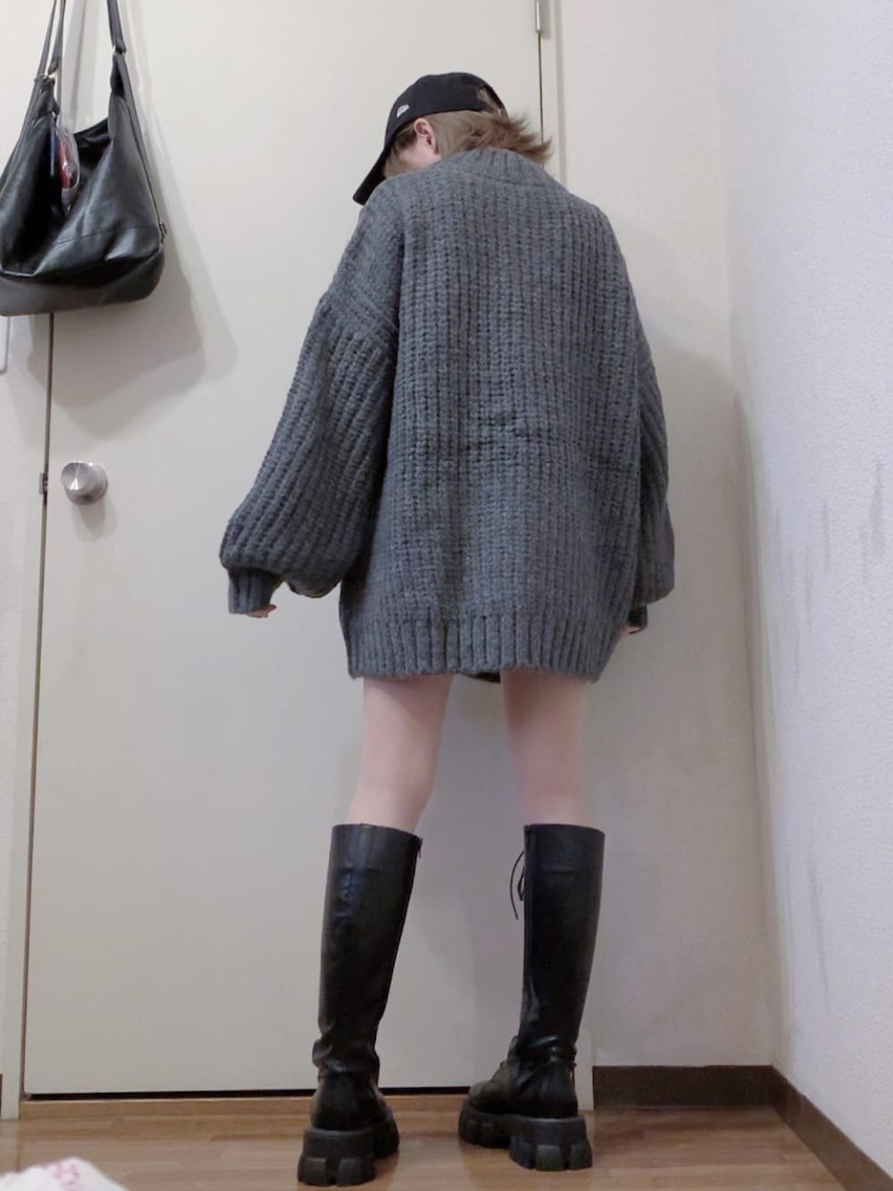 グレー系のニット/セーター、ブラック系のブーツ、ブラック系のダウンジャケット/コートを着用したレディースの冬コーディネートの2枚目の写真