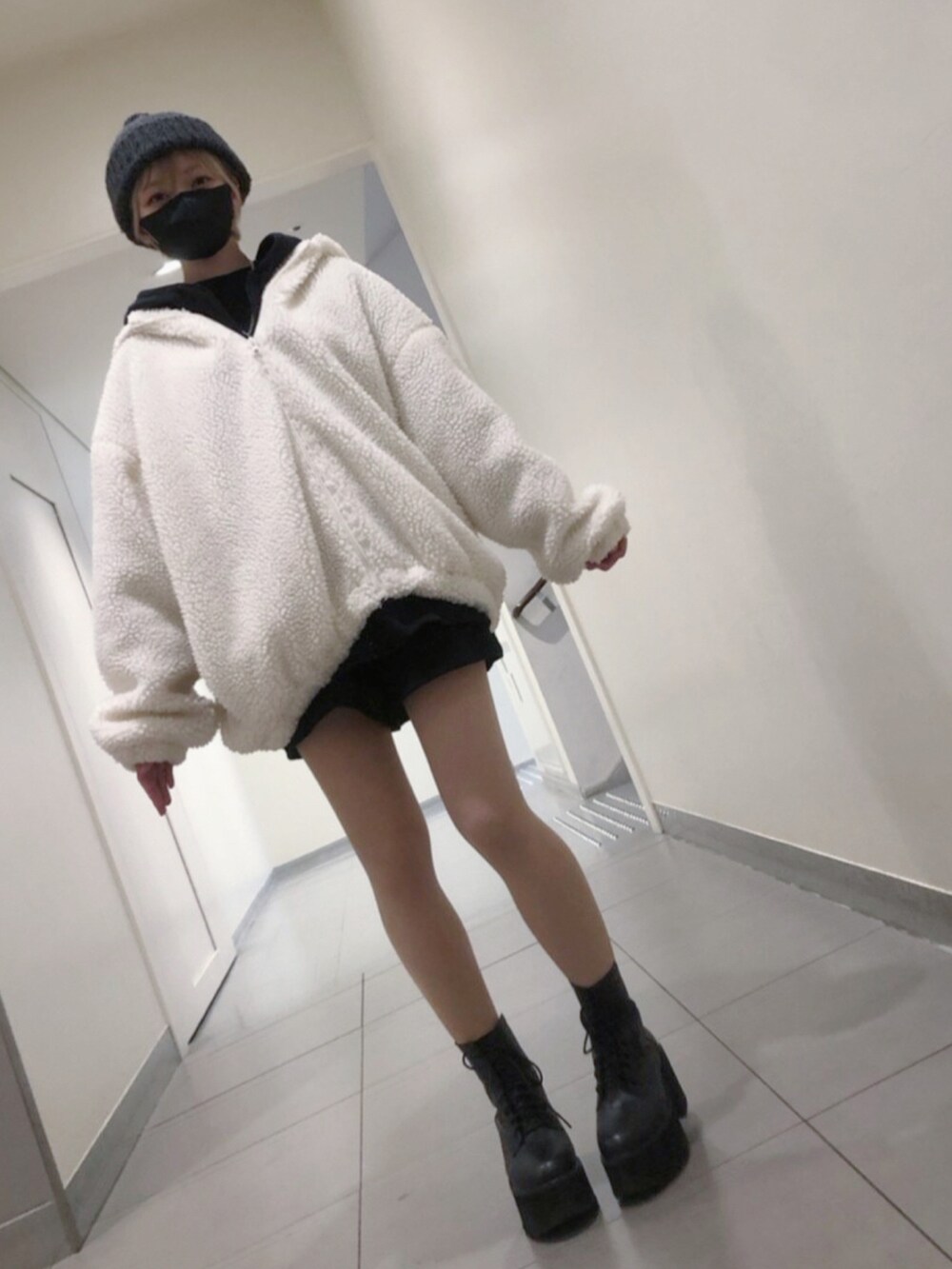ホワイト系のブルゾン、ブラック系のパーカー、ブラック系のニット/セーターを着用したレディースの春コーディネートの2枚目の写真
