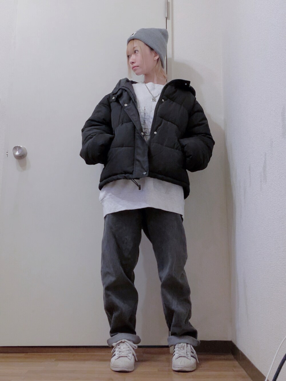 グレー系のスウェット、ブラック系のダウンジャケット/コート、ブラック系のデニムパンツを着用したレディースの冬コーディネートの2枚目の写真