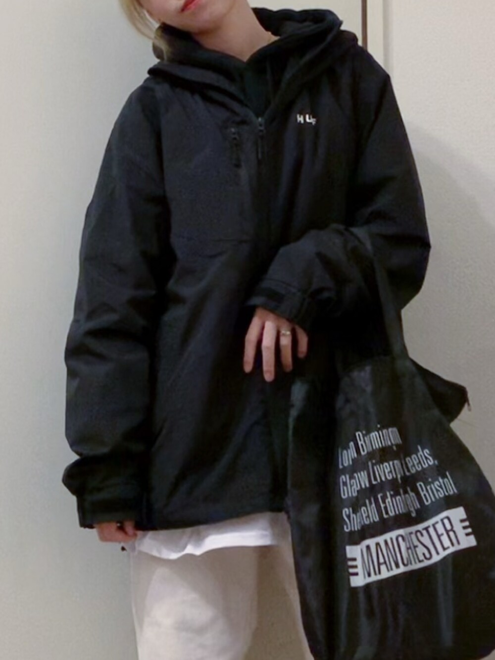 ブラック系のパーカー、ホワイト系のデニムパンツ、ホワイト系のスニーカーを着用したレディースの春コーディネートの4枚目の写真