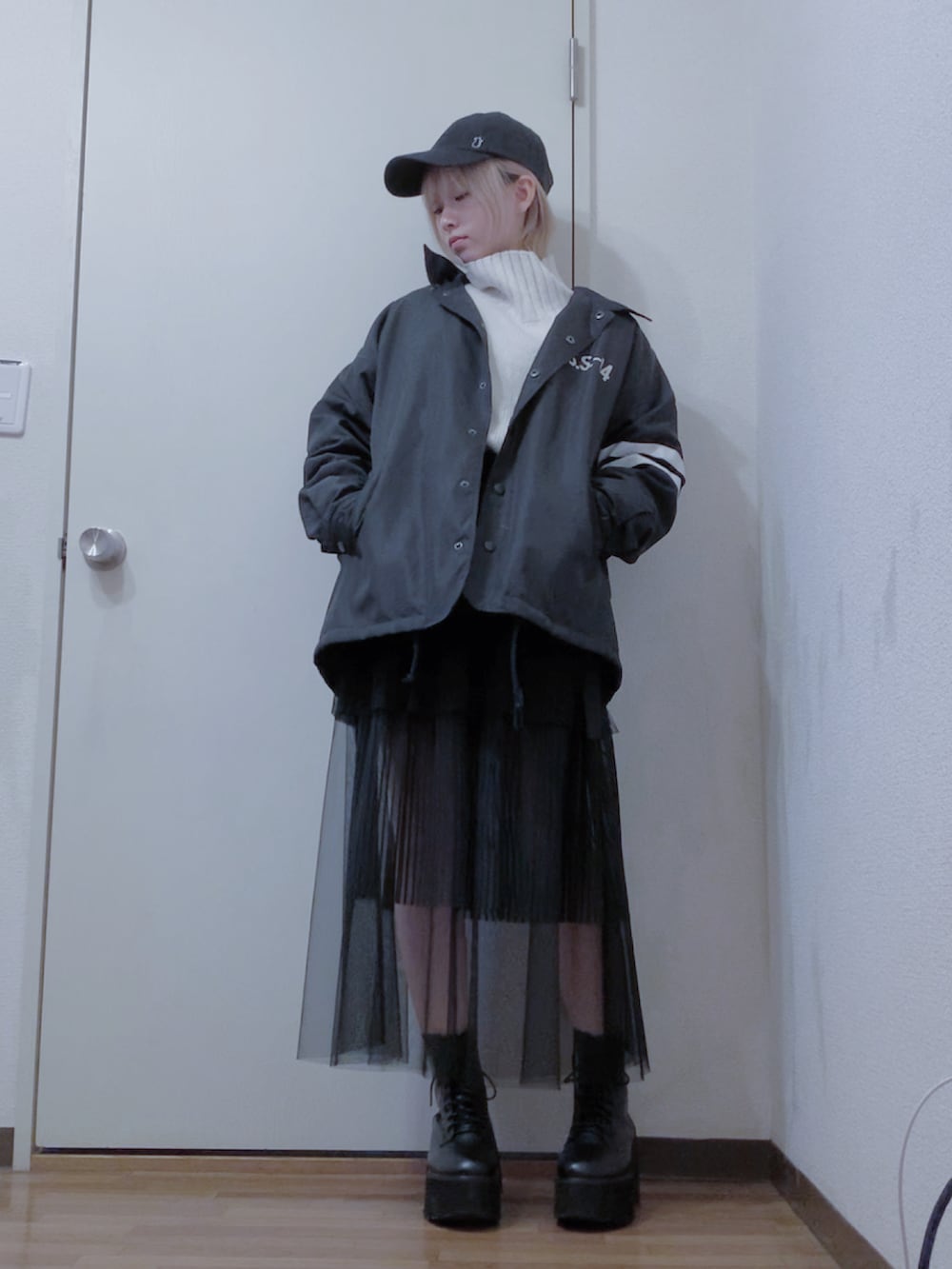 ホワイト系のニット/セーター、ブラック系のスカート、ブラック系のナイロンジャケットを着用したレディースの冬コーディネートの2枚目の写真