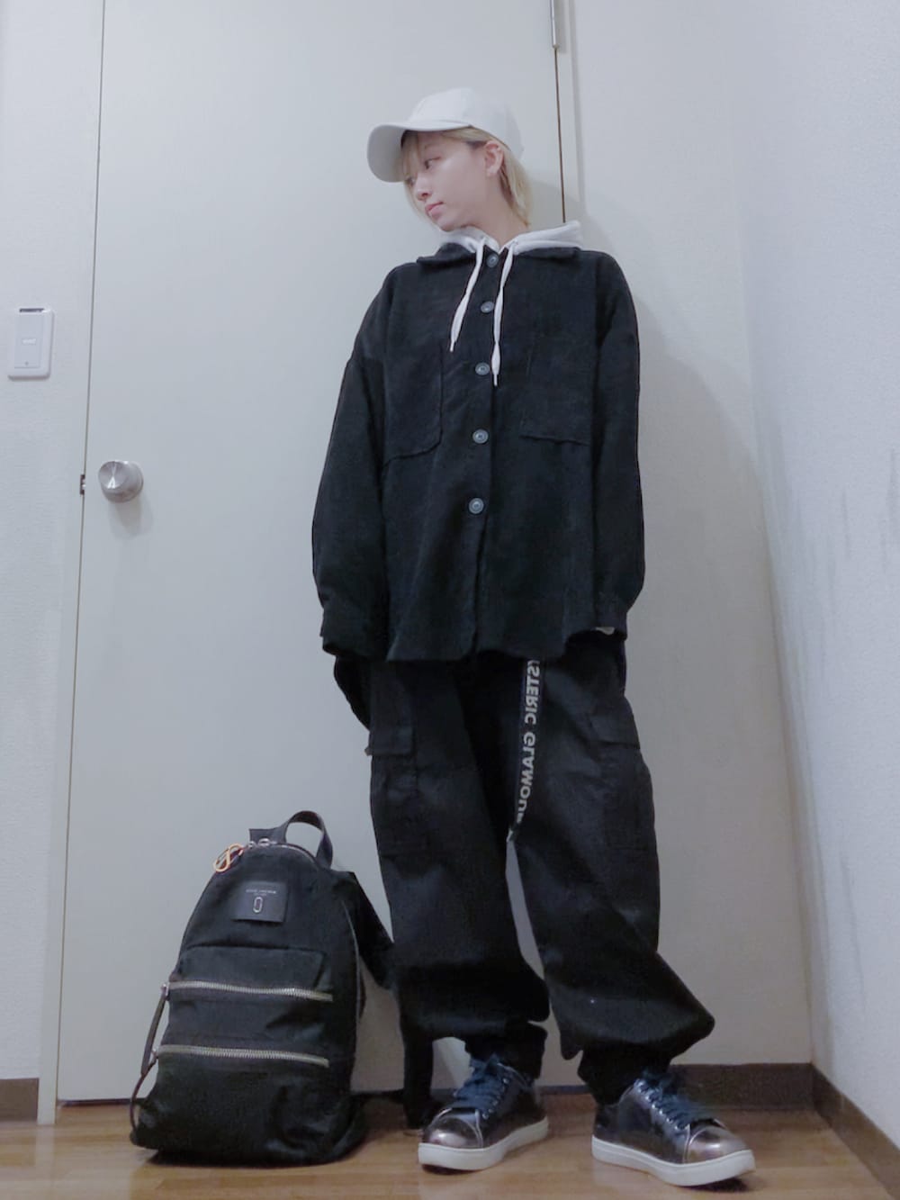 グレー系のパーカー、ブラック系のカバーオール、ブラック系のカーゴパンツを着用したレディースの春コーディネートの2枚目の写真