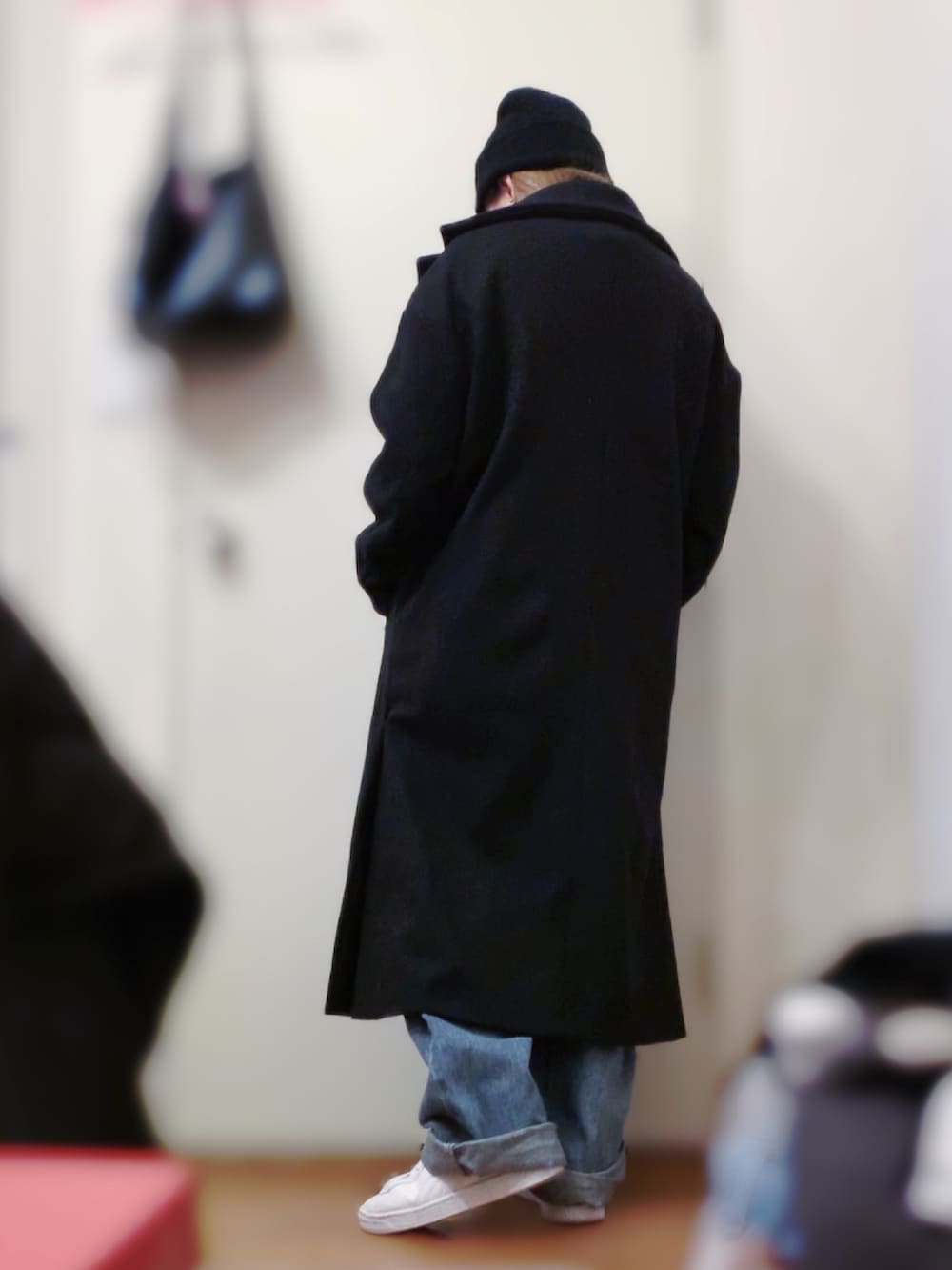 ブラック系のスウェット、ホワイト系のスニーカー、ブラック系のチェスターコートを着用したレディースの春コーディネートの3枚目の写真