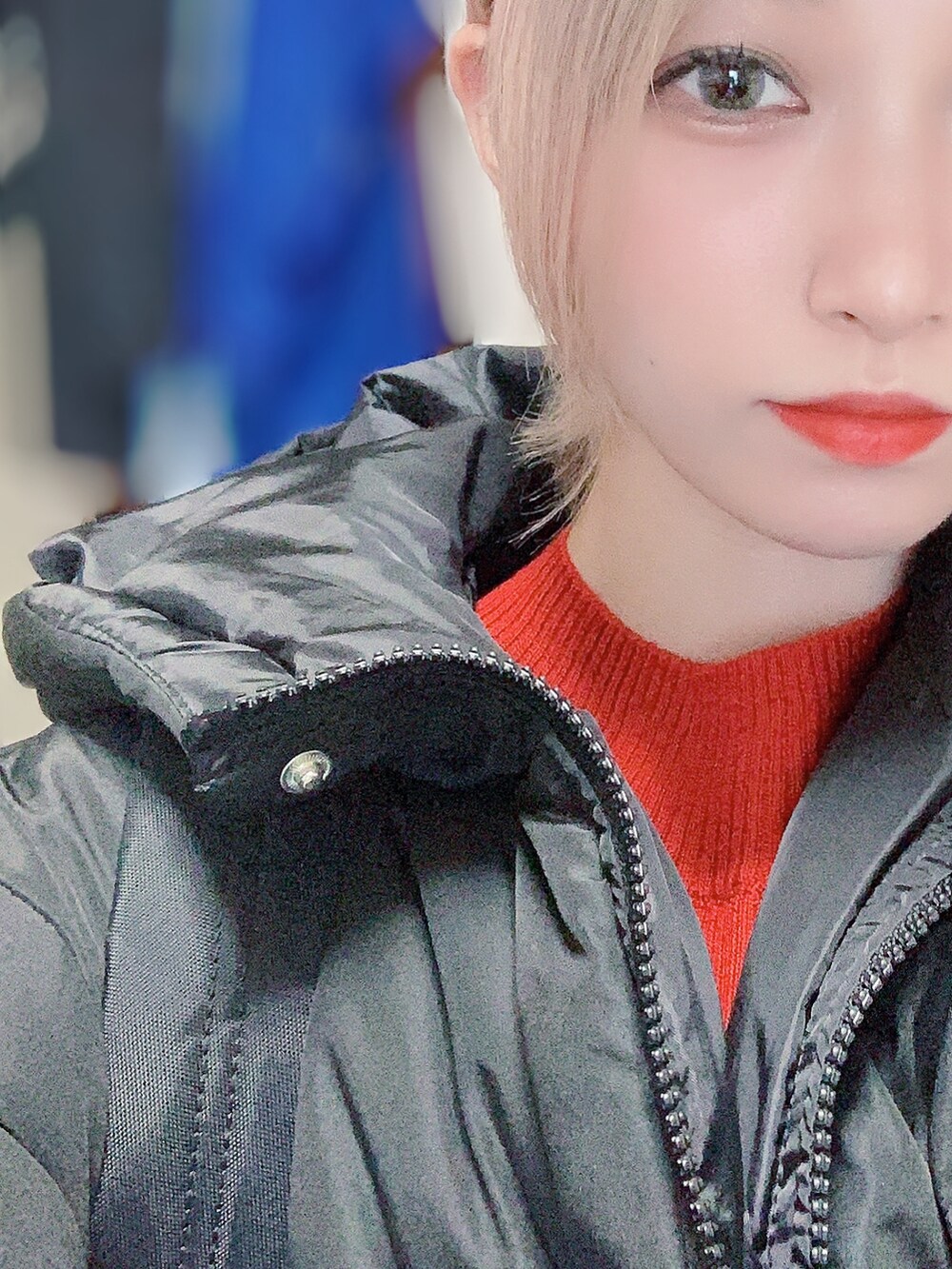 レッド系のニット/セーター、ブラック系のデニムパンツ、ブラック系のダウンジャケット/コートを着用したレディースの冬コーディネートの3枚目の写真