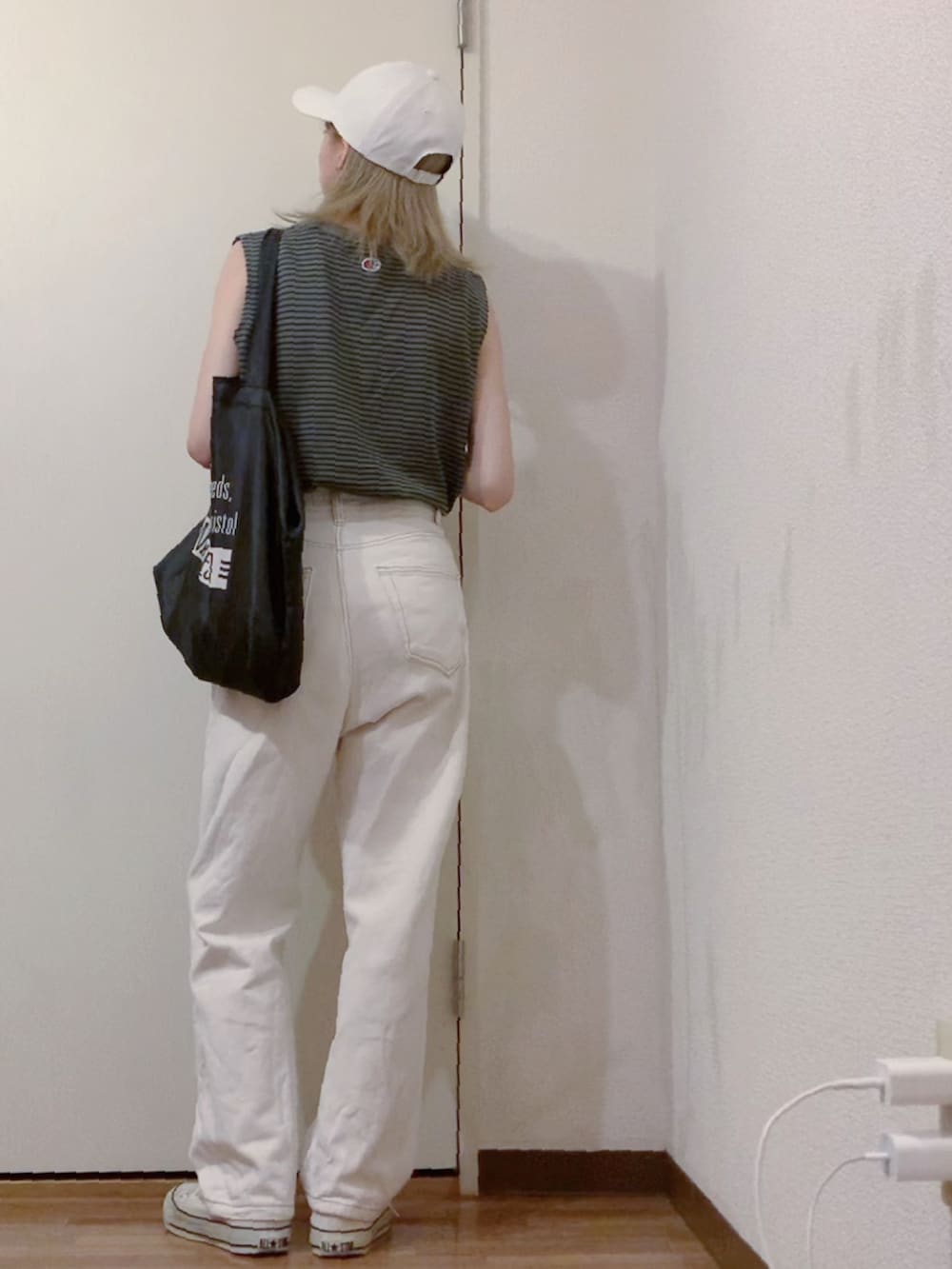 グレー系のタンクトップ、ホワイト系のデニムパンツ、ホワイト系のスニーカーを着用したレディースの夏コーディネートの2枚目の写真