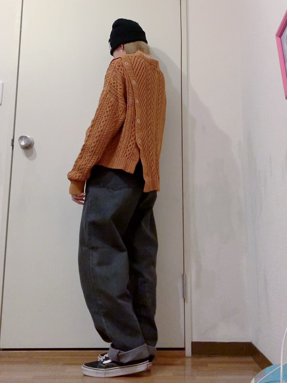 オレンジ系のニット/セーター、ブラック系のデニムパンツ、ブラック系のダウンジャケット/コートを着用したレディースの冬コーディネートの3枚目の写真