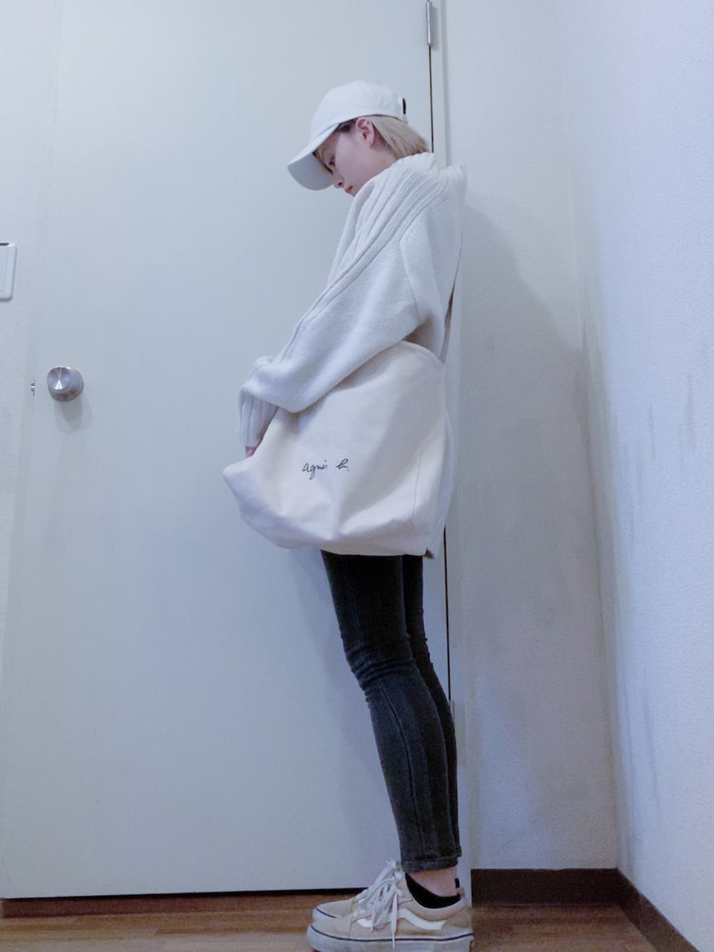 ホワイト系のニット/セーター、ブラック系のデニムパンツ、ベージュ系のスニーカーを着用したレディースの春コーディネートの2枚目の写真