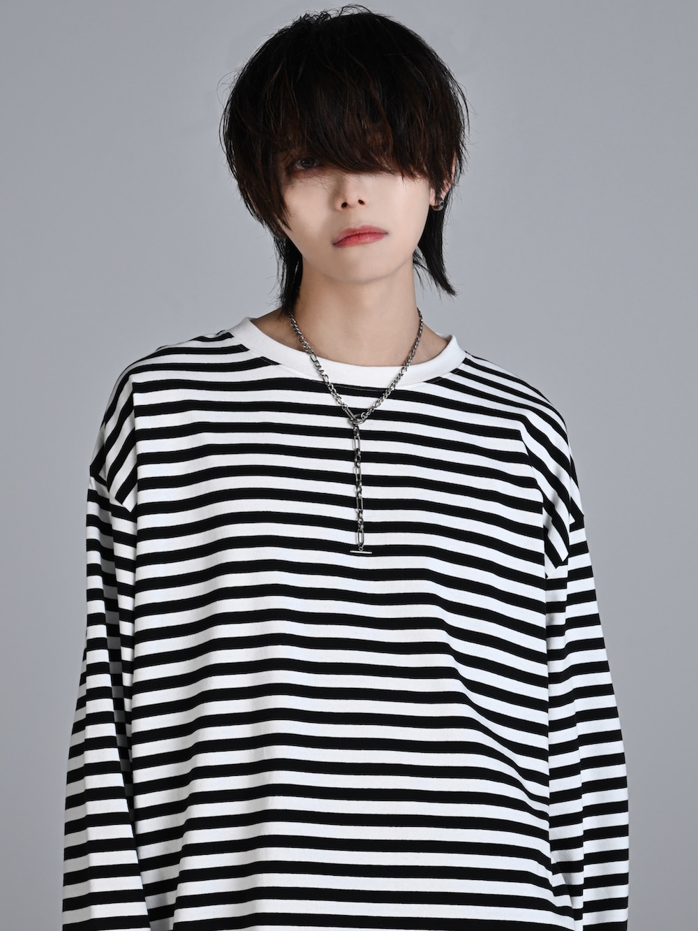 ブラック系のデニムパンツ、ホワイト系のスニーカー、ブラック系のショルダーバッグを着用したメンズの秋コーディネートの2枚目の写真