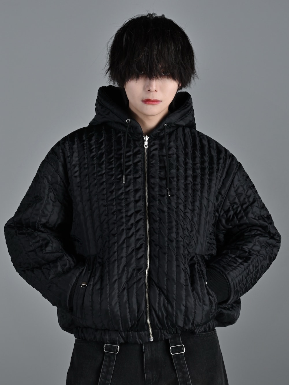 ブラック系のブルゾン、ブラック系のデニムパンツ、ホワイト系のスニーカーを着用したメンズの冬コーディネートの3枚目の写真